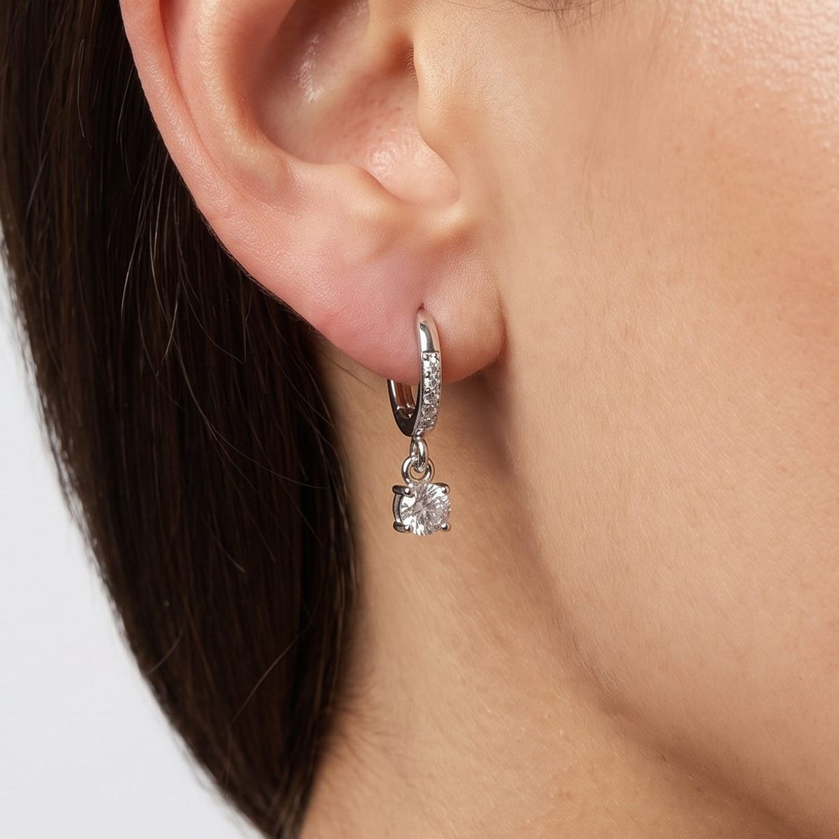 Woman wearing the Vittoria Crystal Silver Earrings hanging below the lobe with a dangling round crystal charm