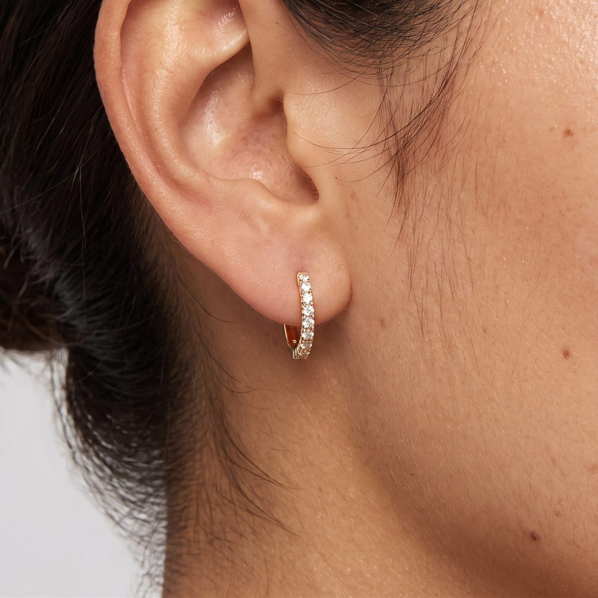 Woman wearing the Alexandria Crystal Huggie Earrings through the lobe featuring a row of small crystals