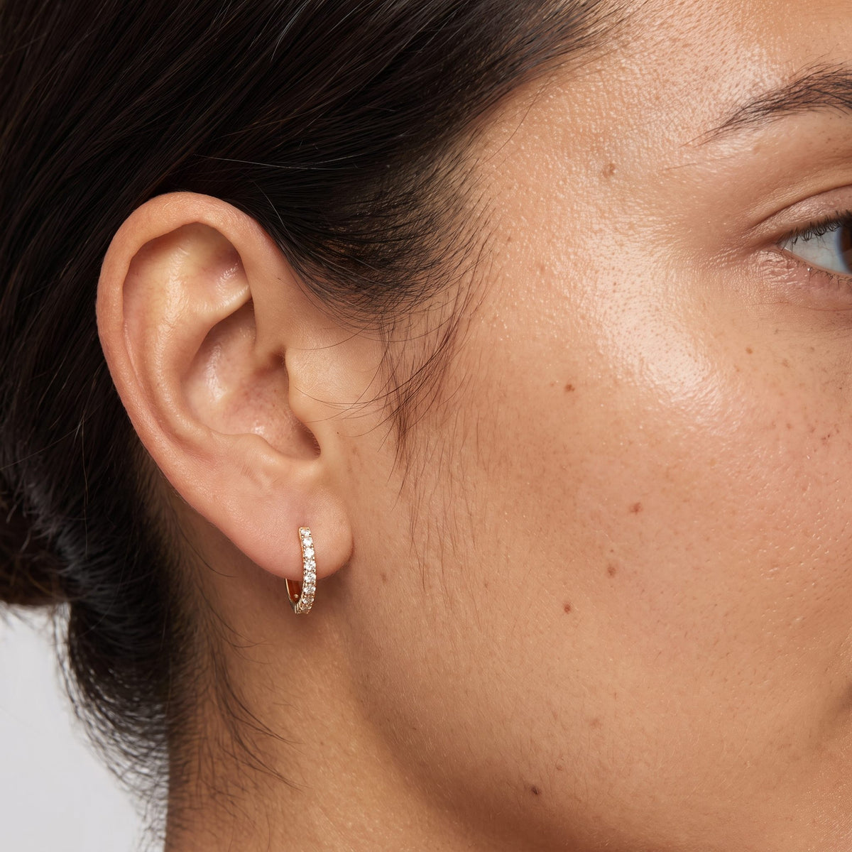 Woman wearing the Alexandria Crystal Huggie Earrings through the lobe featuring a row of small crystals