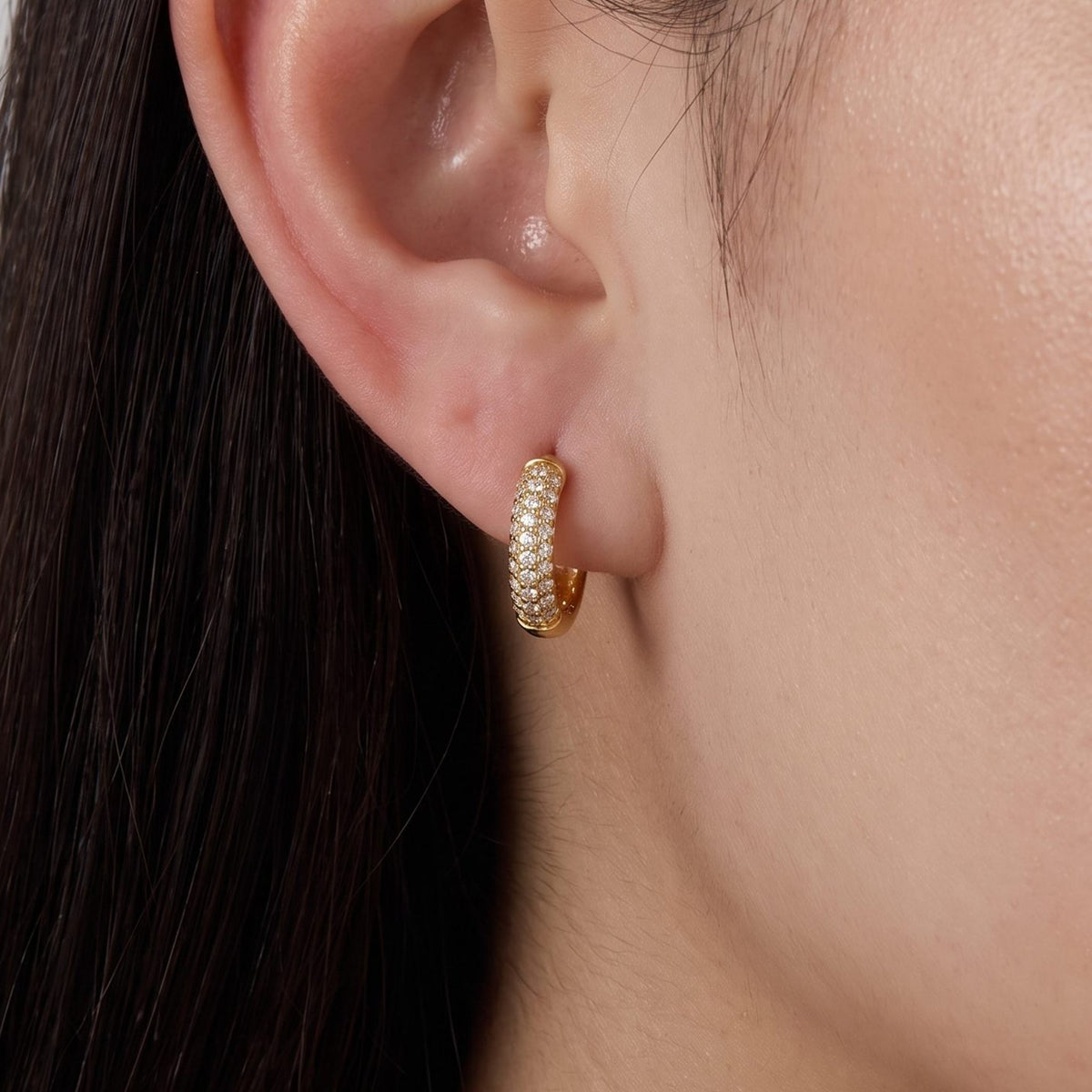 Close view of a woman wearing the Amelia Chunky Crystal Huggies paved with crystals on the lobe