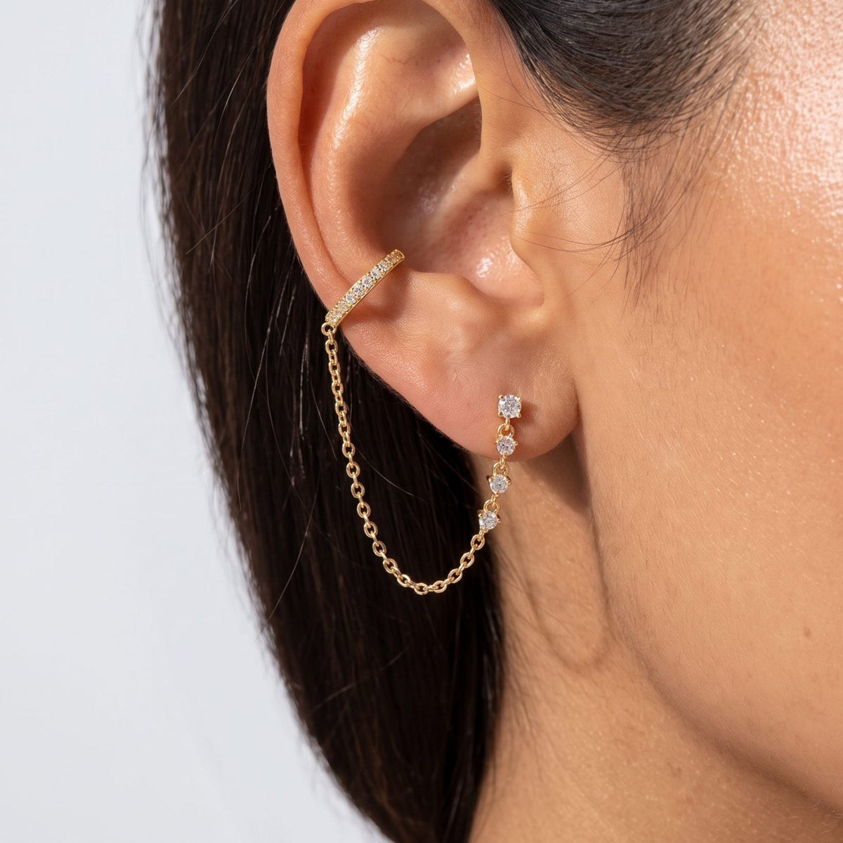 Woman wearing the Andra Chain Cuff Earrings on her ear with a gold chain draping below the lobe