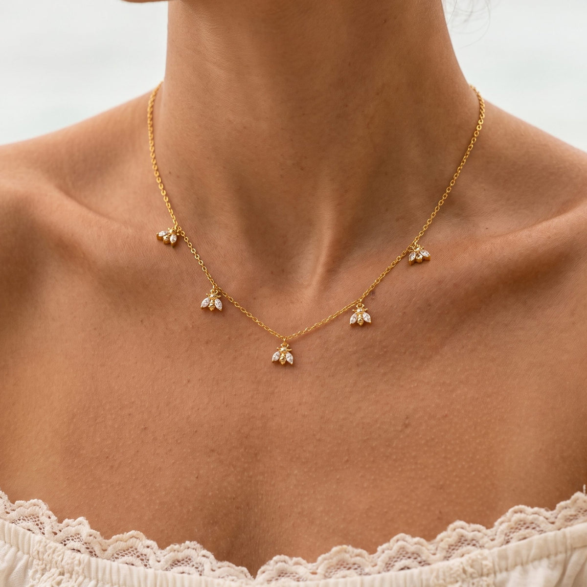 Close-up of the Bee Charm Necklace worn on the neckline