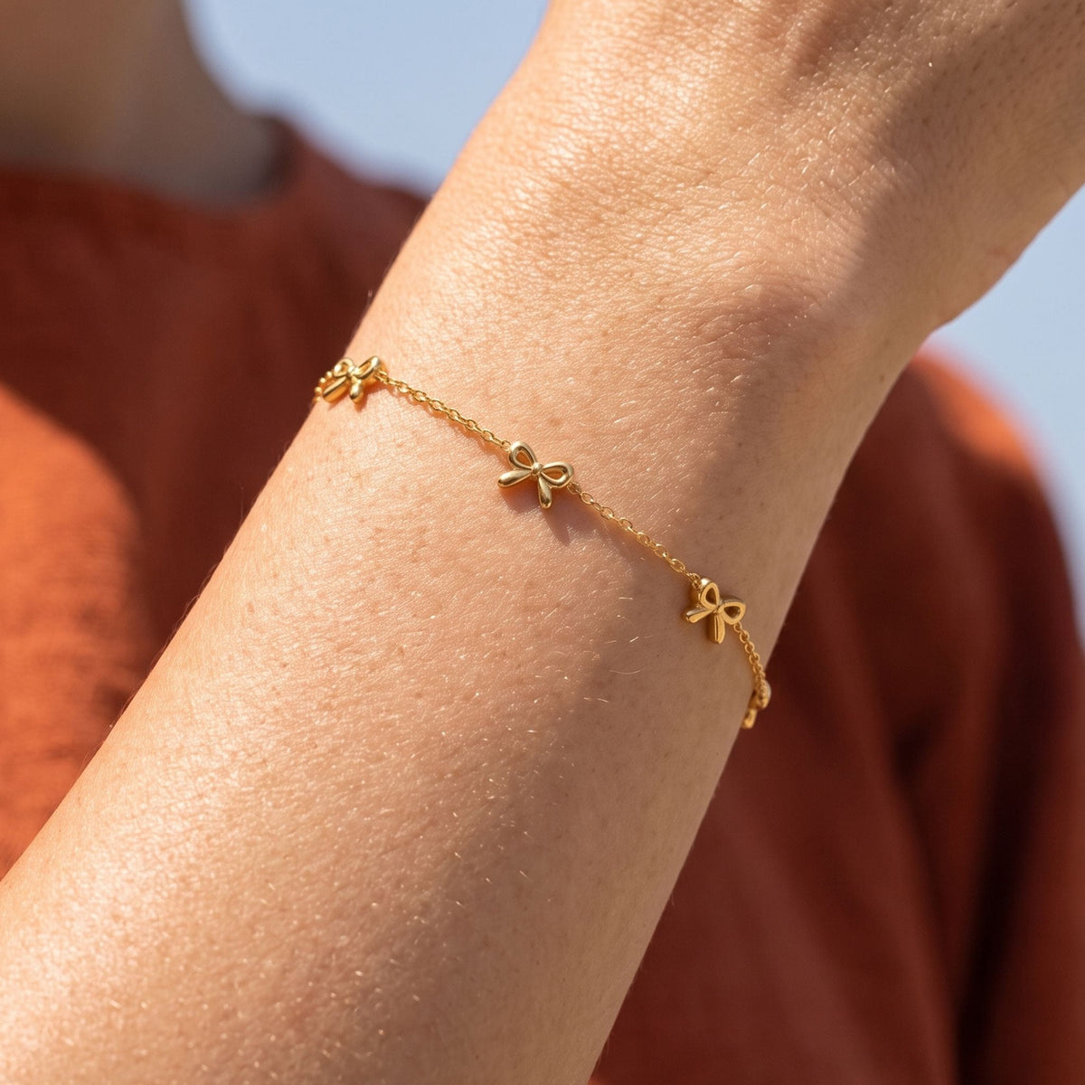 Bow Chain Bracelet worn on the wrist, photographed in natural daylight.