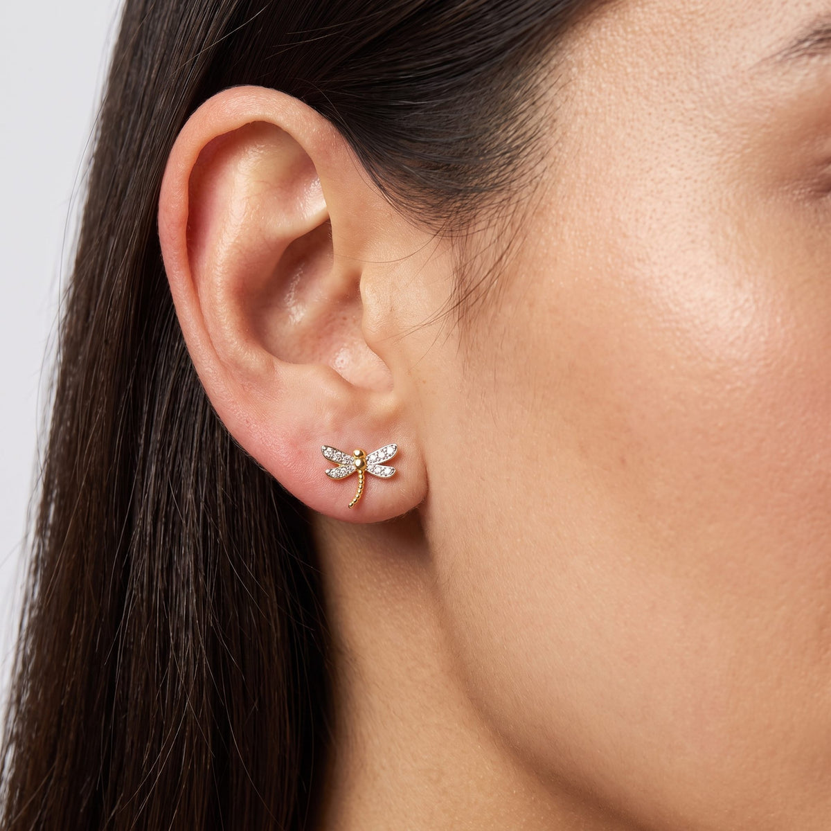 Woman wearing the Camila Dragonfly Stud Earrings flat to the lobe with sparkling wings