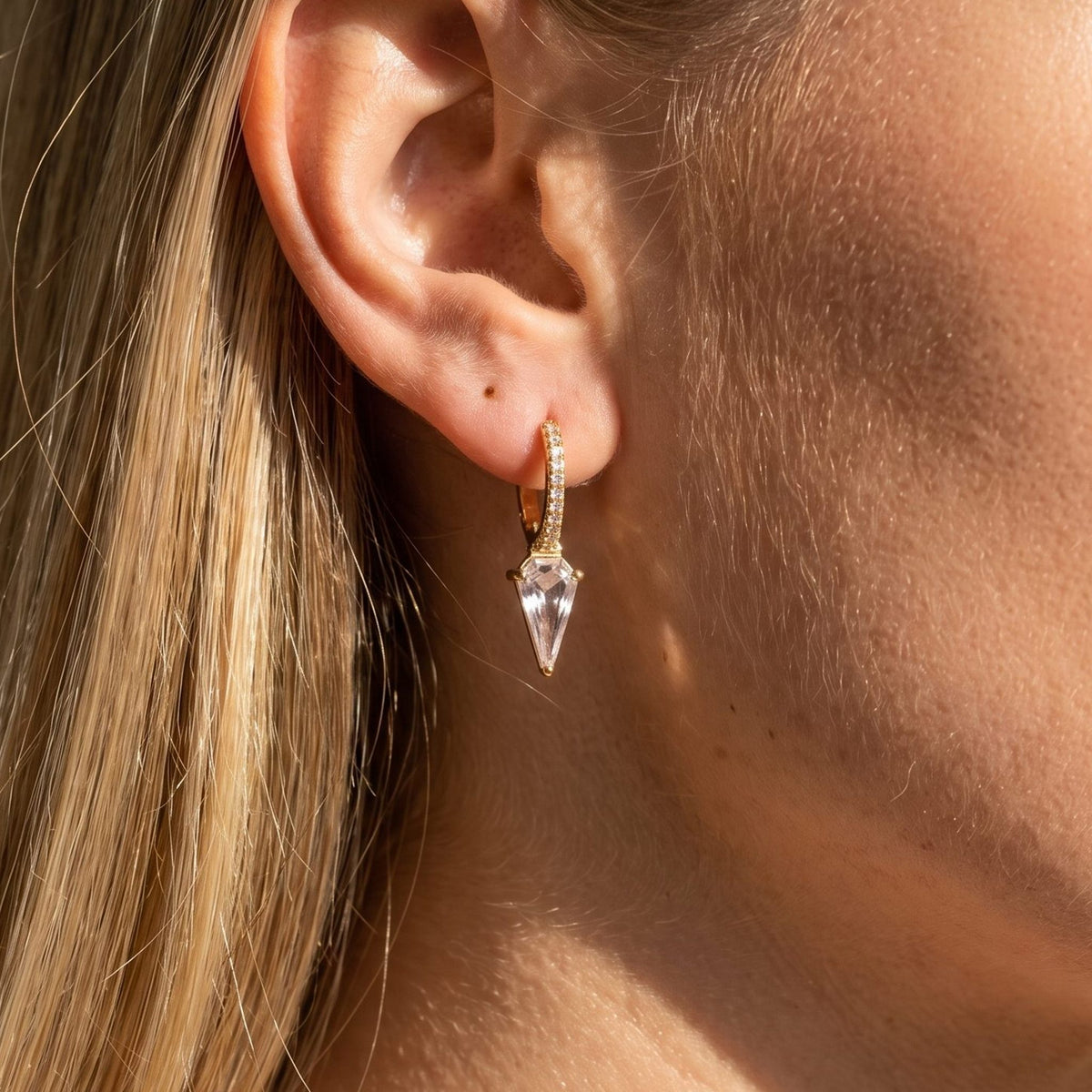 Woman wearing the Camila Prism Drop Earrings hanging below the lobe with a pointed clear crystal