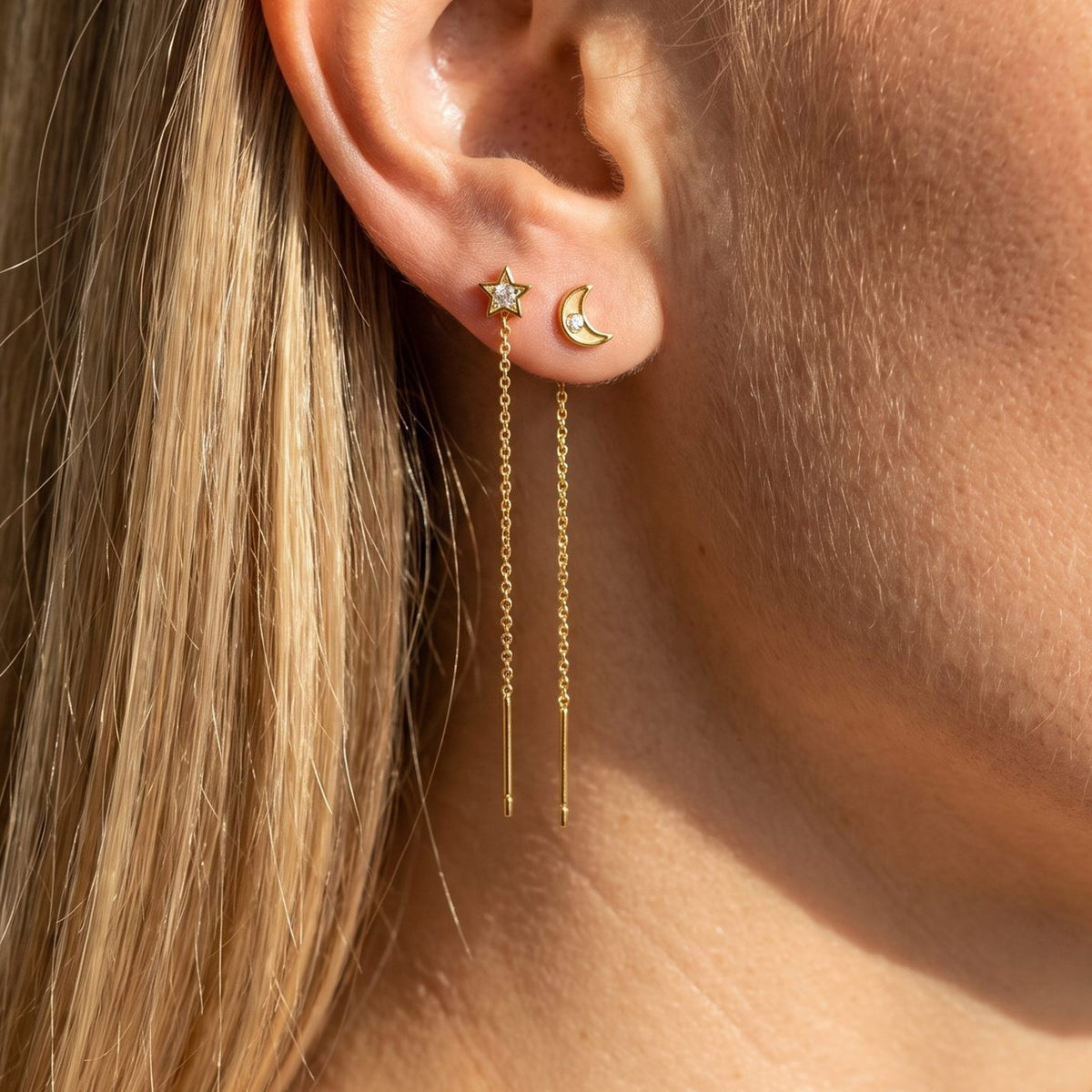 Woman wearing the Camille Drop Chain Earrings hanging below the lobe with star and moon studs
