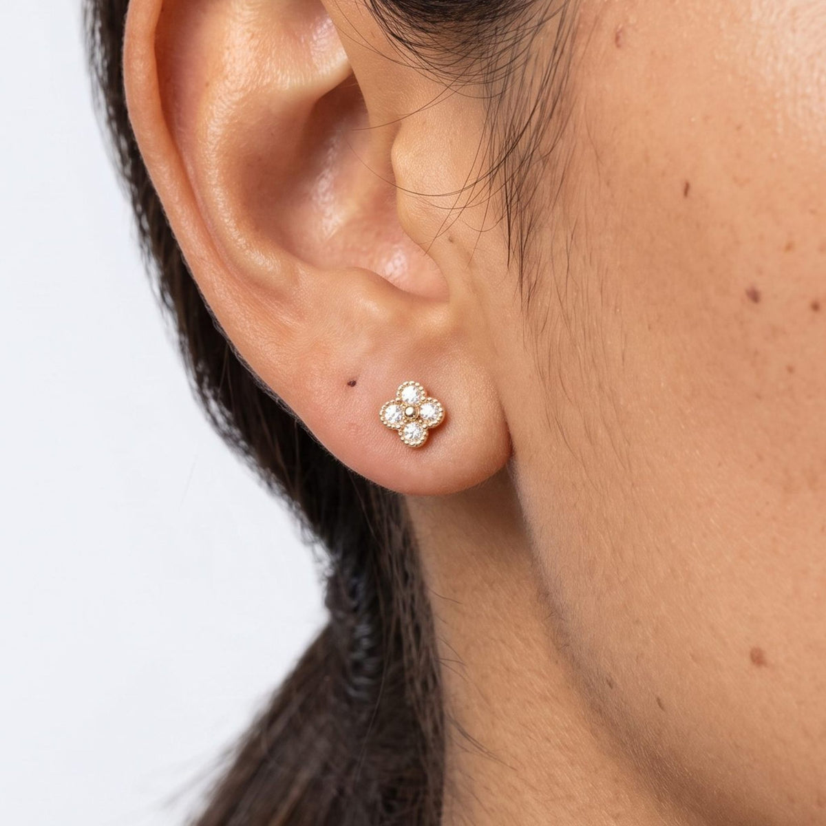 Woman wearing the Cassidy Sparkle Stud Earrings on the lobe, featuring a gold flower shape