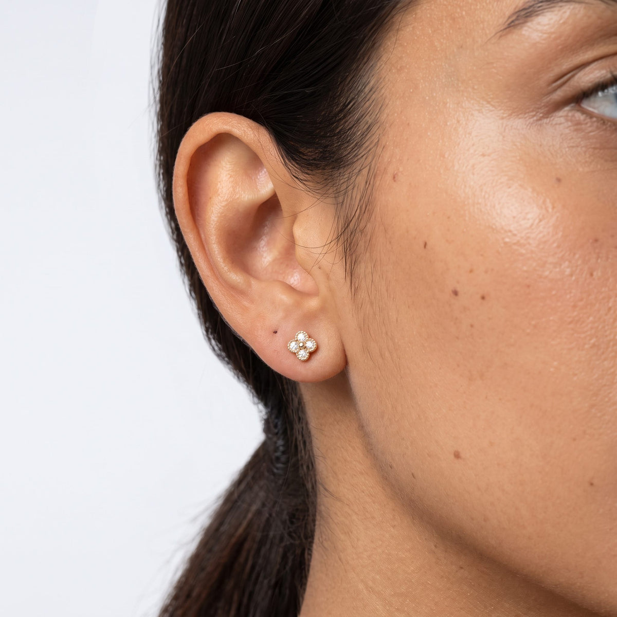 Woman wearing the Cassidy Sparkle Stud Earrings on the lobe, featuring a gold flower shape