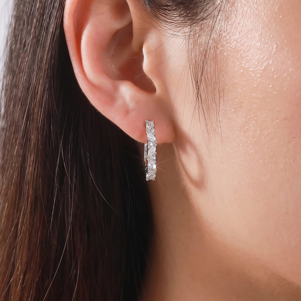 Woman wearing the Celeste Pavé Hoop Earrings on her lobe, featuring sparkling silver-colored stones