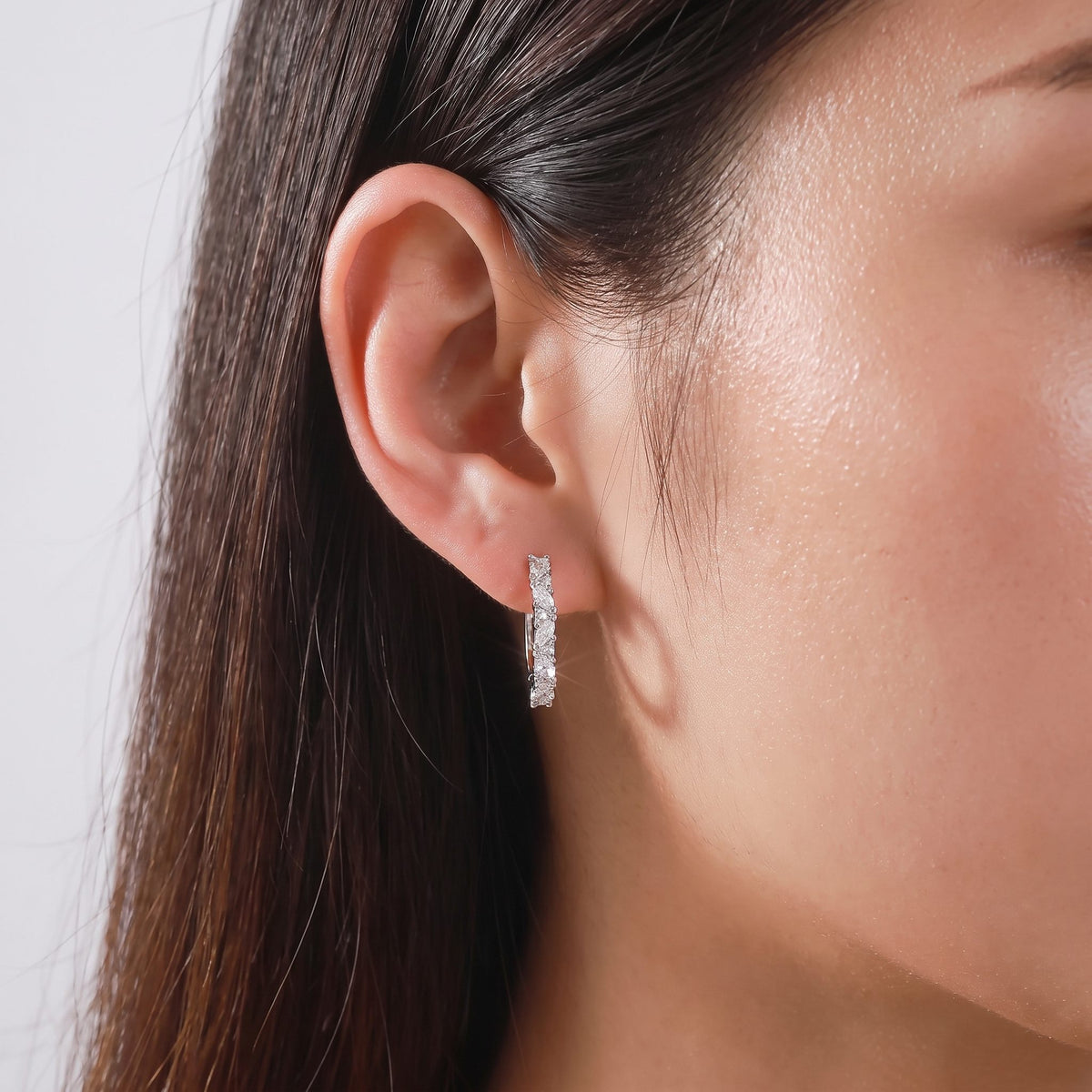 Woman wearing the Celeste Pavé Hoop Earrings on her lobe, featuring sparkling silver-colored stones