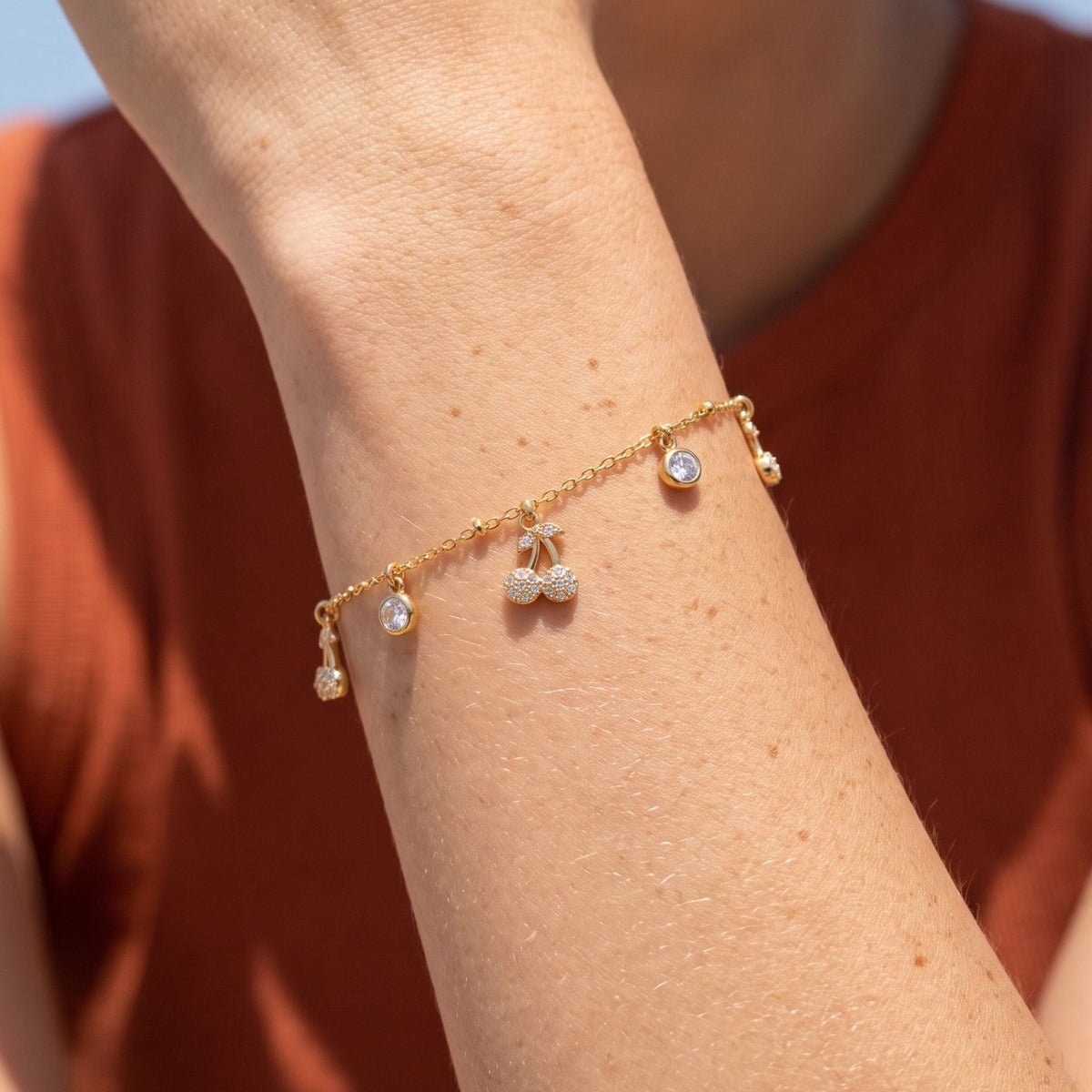 Cherry Charm Bracelet worn on the wrist, photographed in natural daylight.