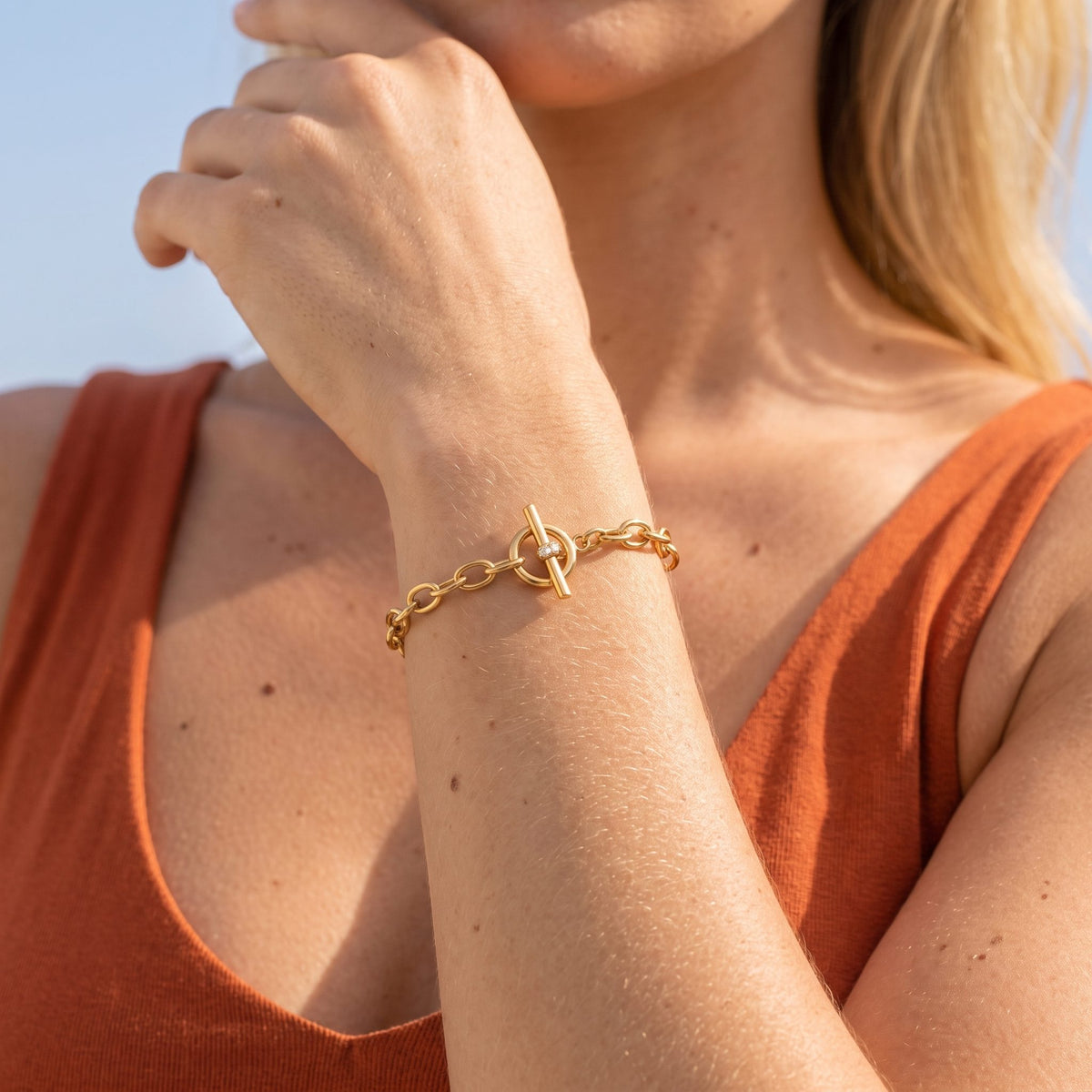 Woman wearing the Circle Toggle Bracelet on her wrist, resting her hand near her chin