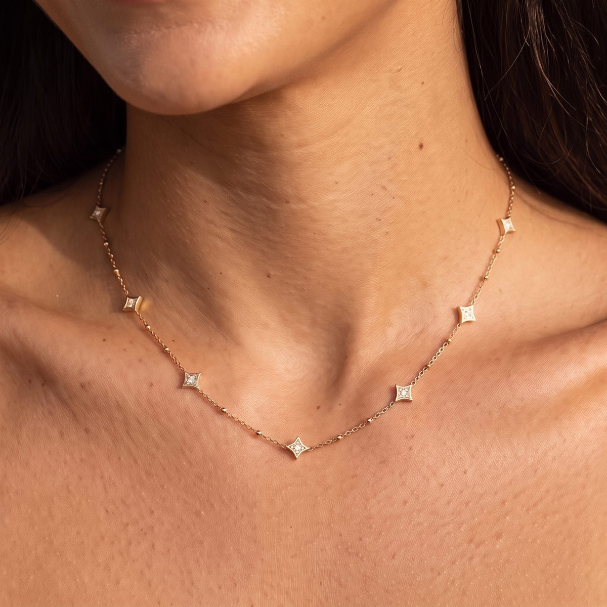 Close-up of the Constellation Necklace at the collarbone, featuring delicate star pendants with crystals, in rose gold
