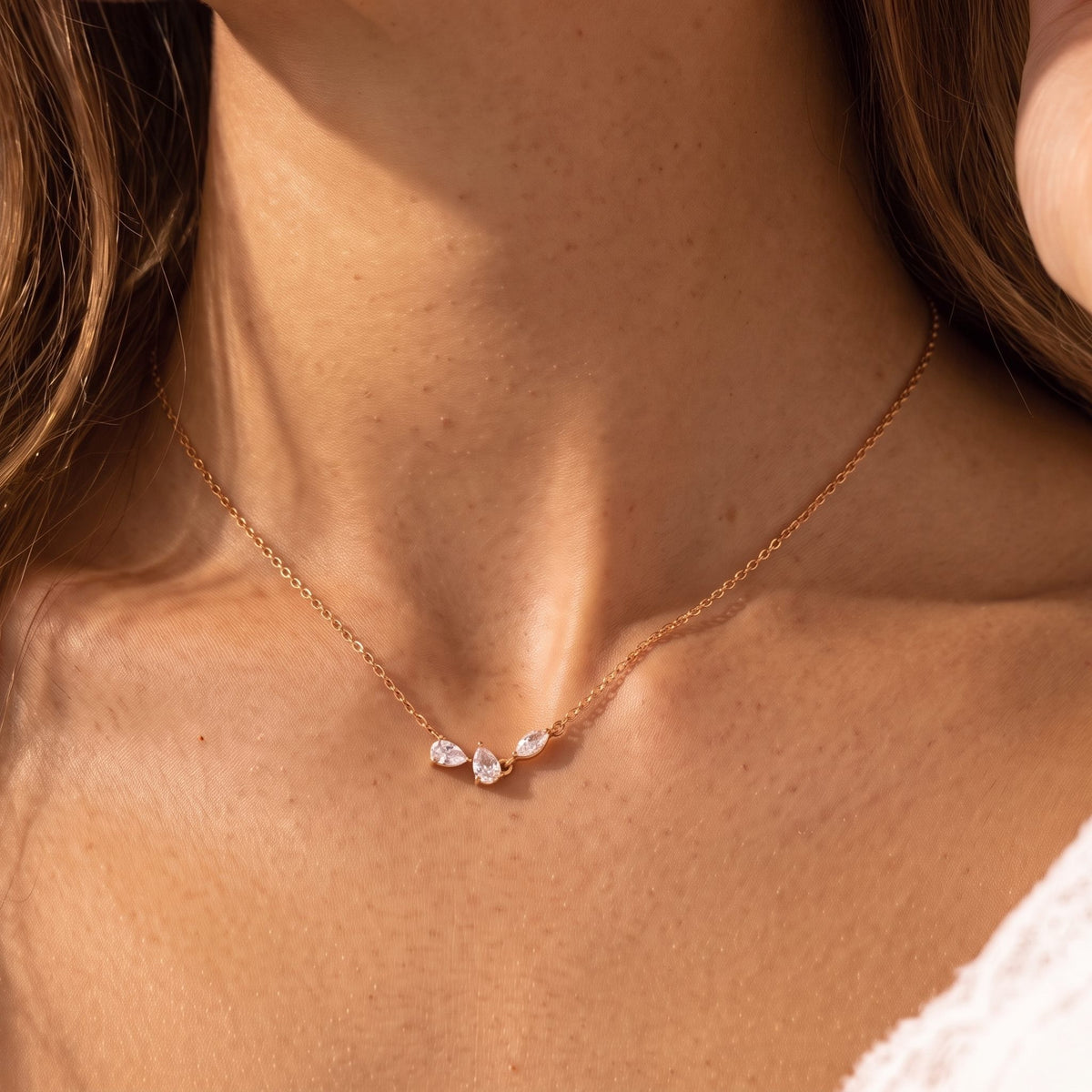 Close-up of the Crystal Petal Necklace at the collarbone, showing three delicate crystal petals, in rose gold