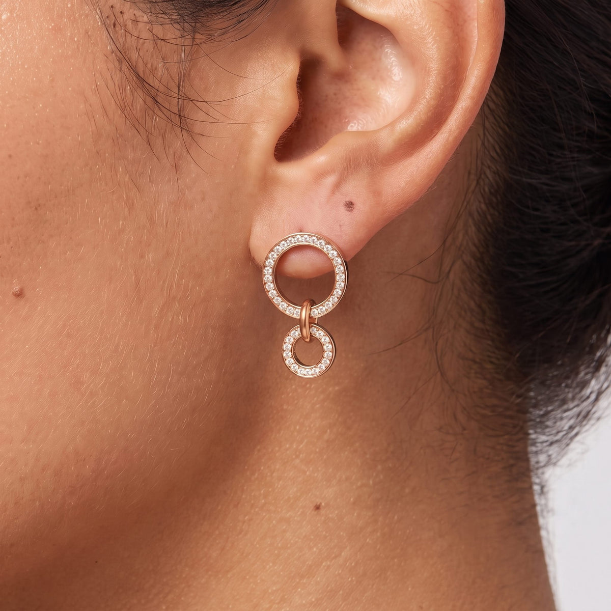 Close-up of the Double Circle Earrings on an ear, showing pave-set sparkling crystals, in rose gold