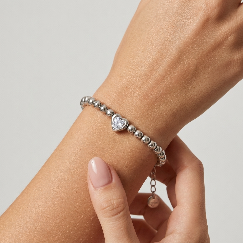 Aurélie heart beaded silver bracelet on the wrist, a hand adjusting it near the extender chain