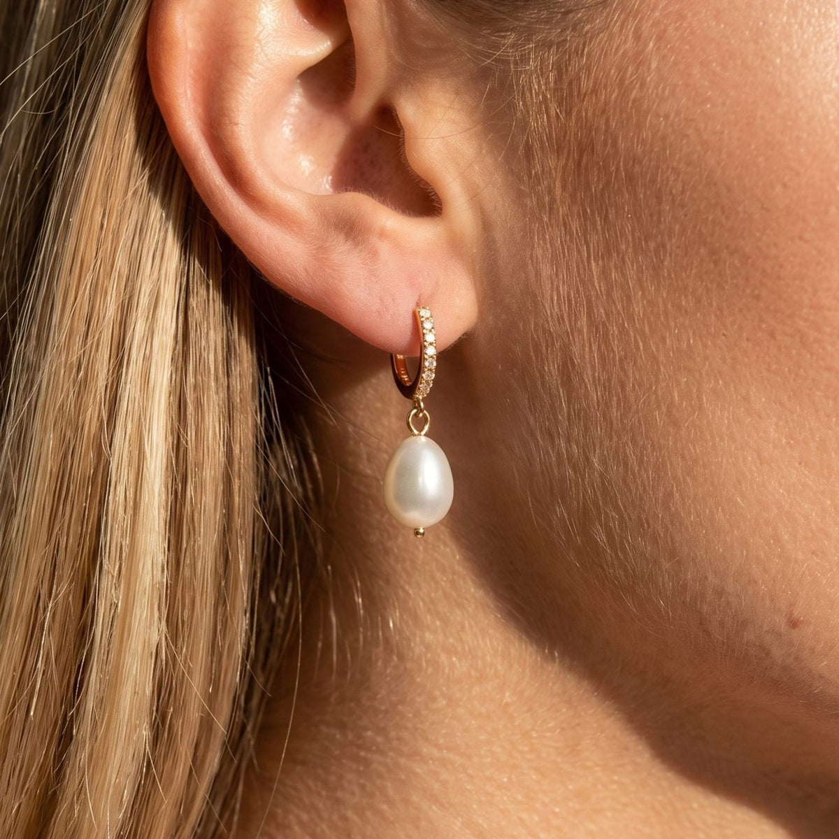 Woman wearing the Élise Baroque Pearl Earrings hanging below the lobe on a gold hoop