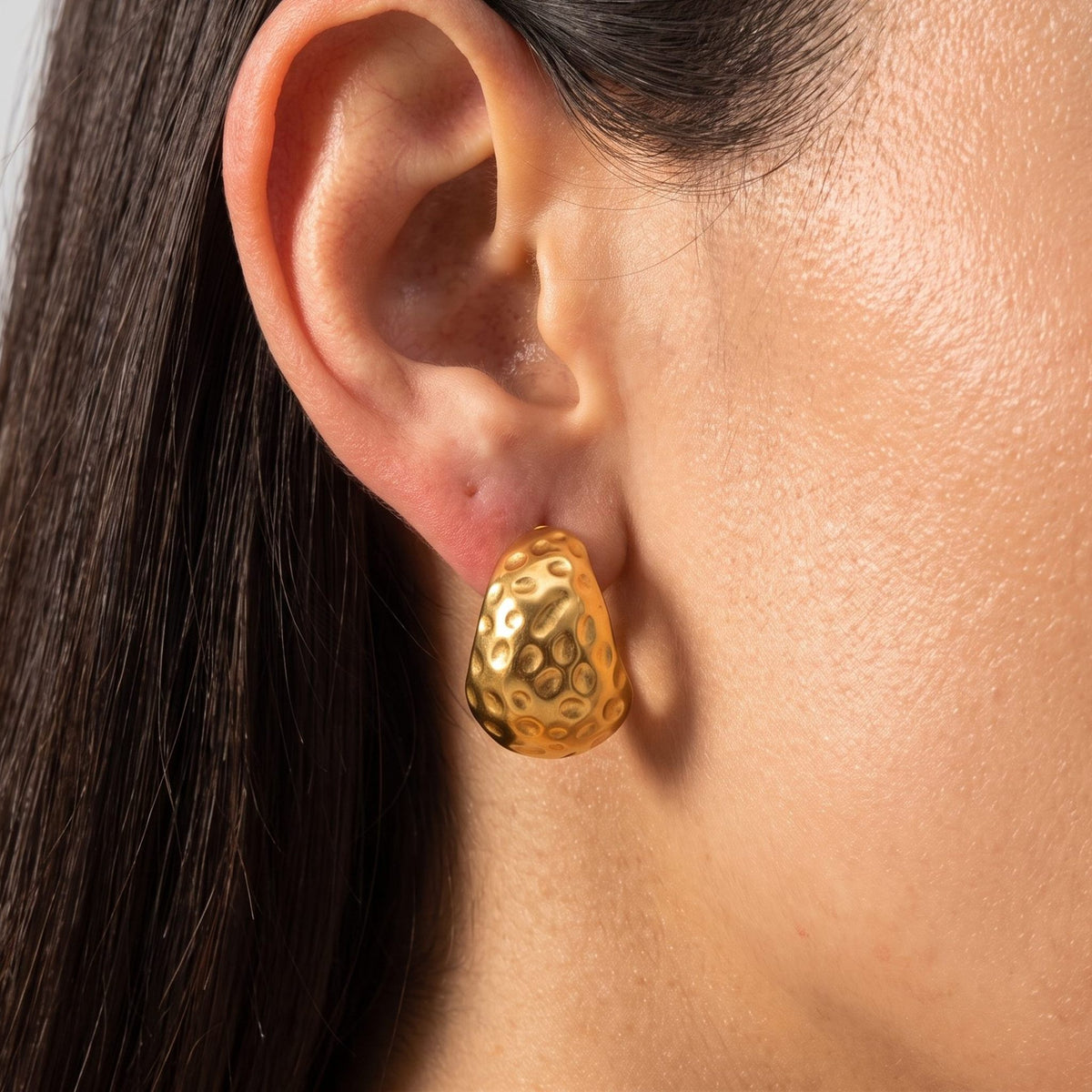 Woman wearing the Elliana Gold Earrings on her lobe, featuring a chunky hammered texture