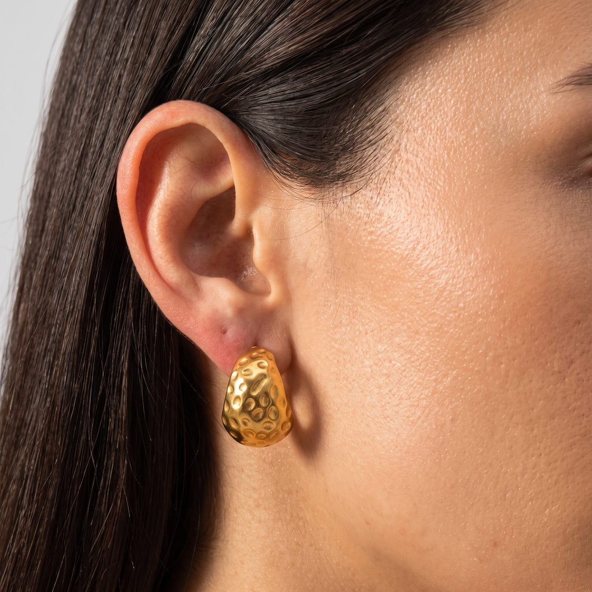 Woman wearing the Elliana Gold Earrings on her lobe, featuring a chunky hammered texture