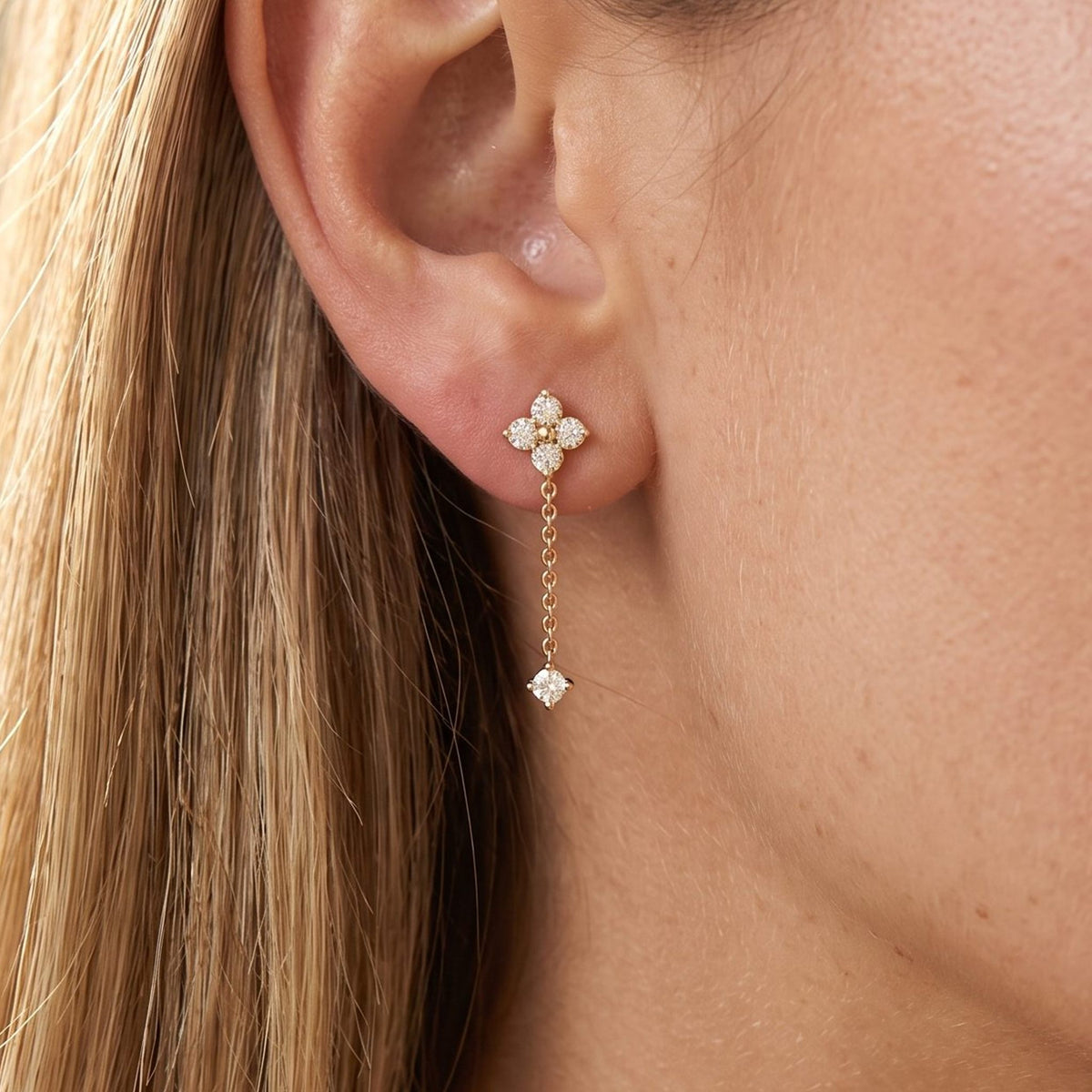 Close view of a woman wearing the Emma Clover Crystal Drop Earrings with a delicate gold chain hanging below the lobe