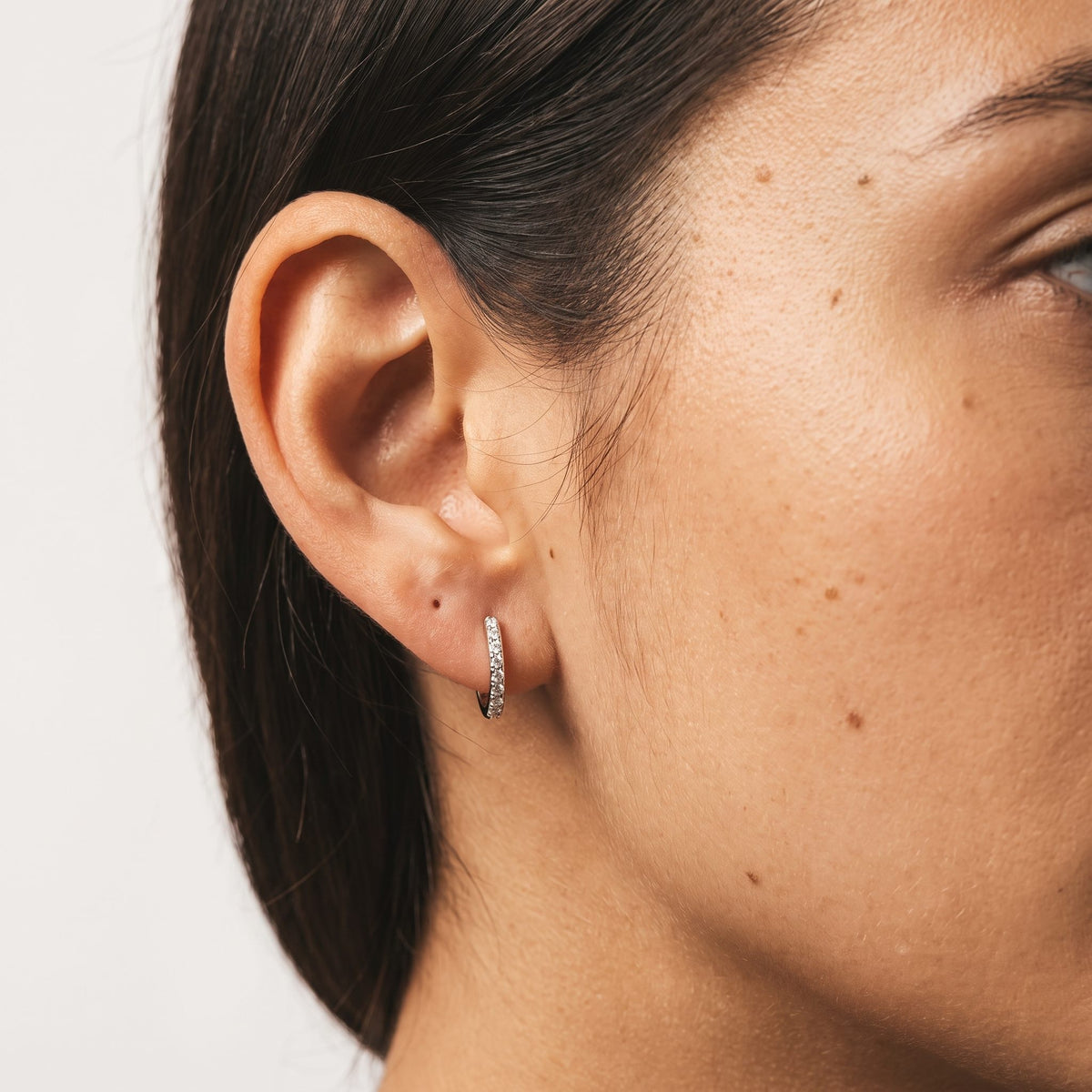 Close view of a woman wearing the Emma Pavé Silver Hoops through the lobe with tiny shimmering stones