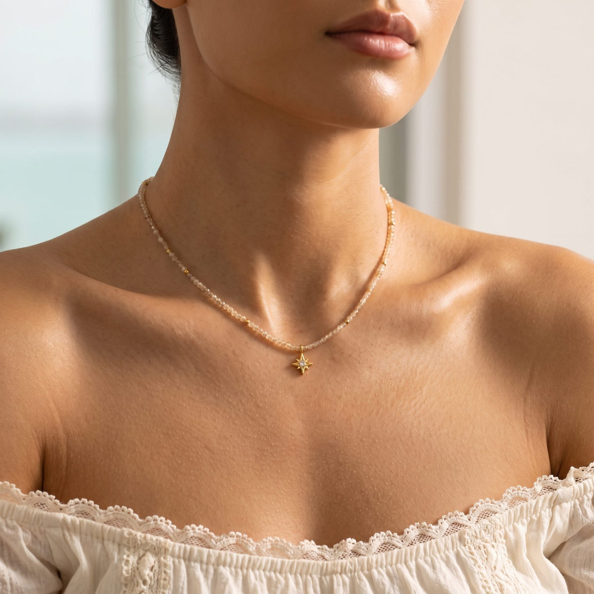 Woman wearing the Faceted Bead Necklace at the collarbone in an off-the-shoulder lace top