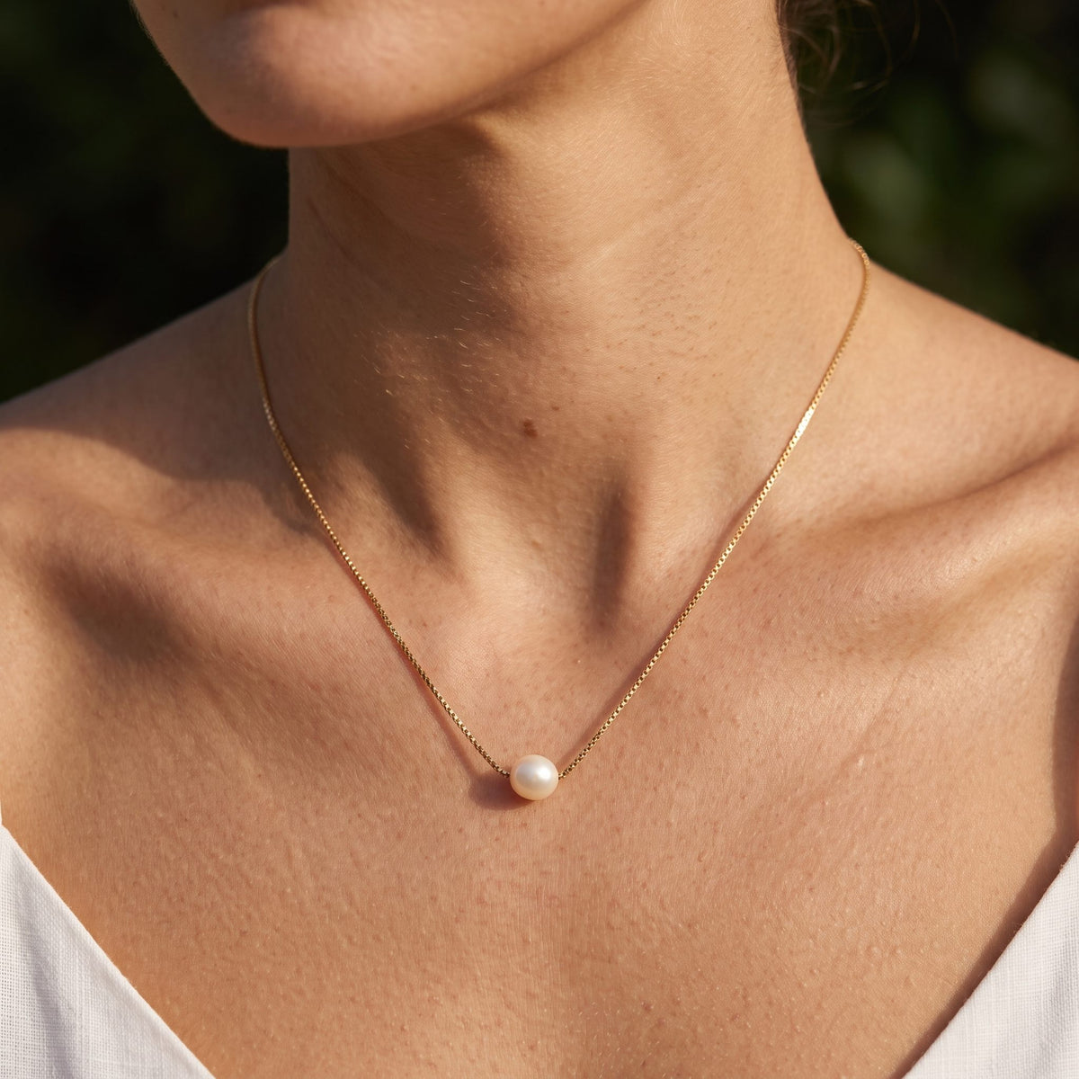Woman wearing the Floating Pearl Pendant on the neckline