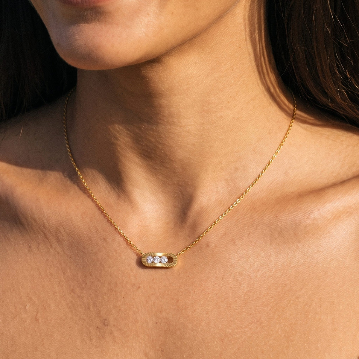 Close-up of the Fluted Trio Necklace at the collarbone showing three sparkling crystals in a gold oval pendant