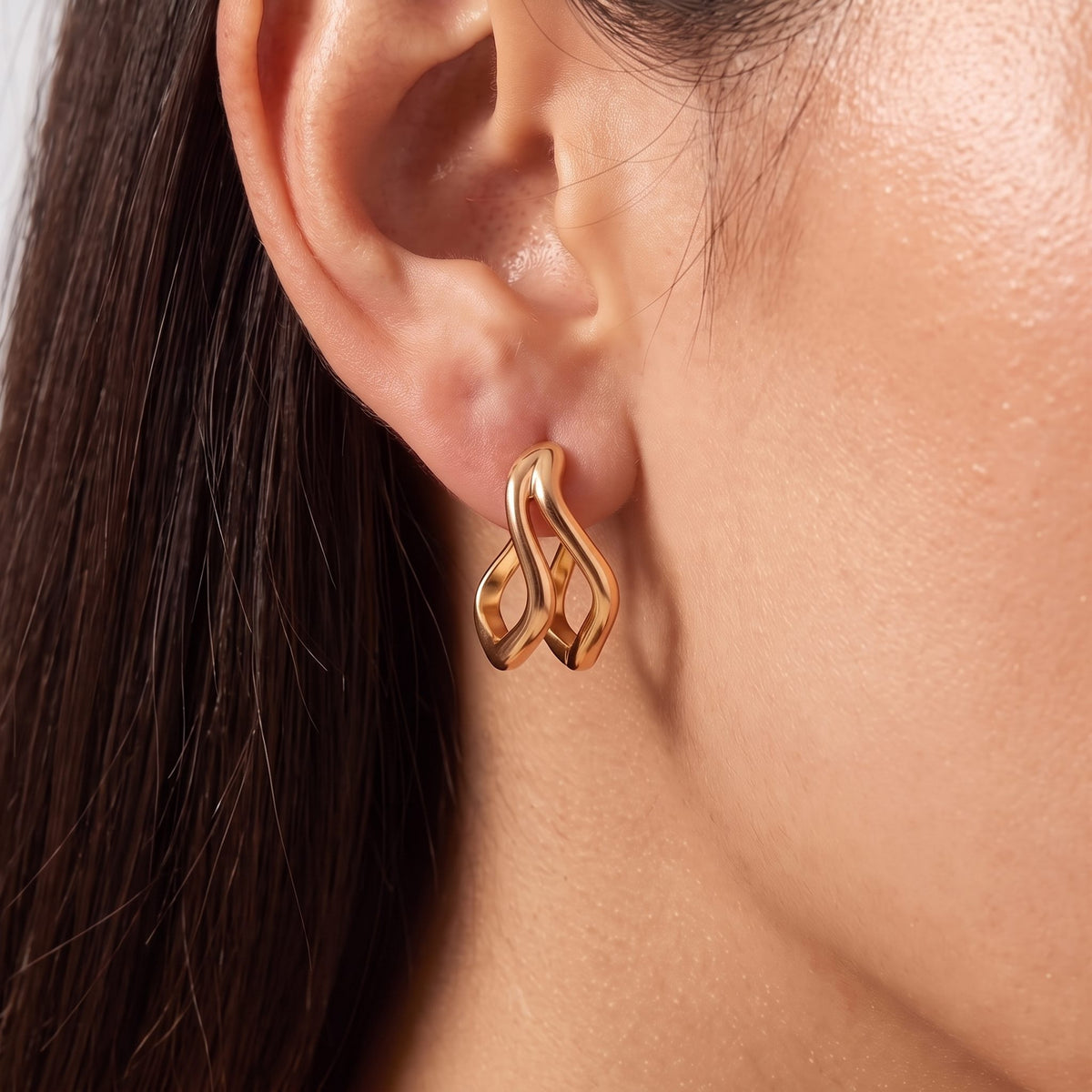 Close-up of the rose gold Double Wave Hoops on the ear highlighting their polished curved design
