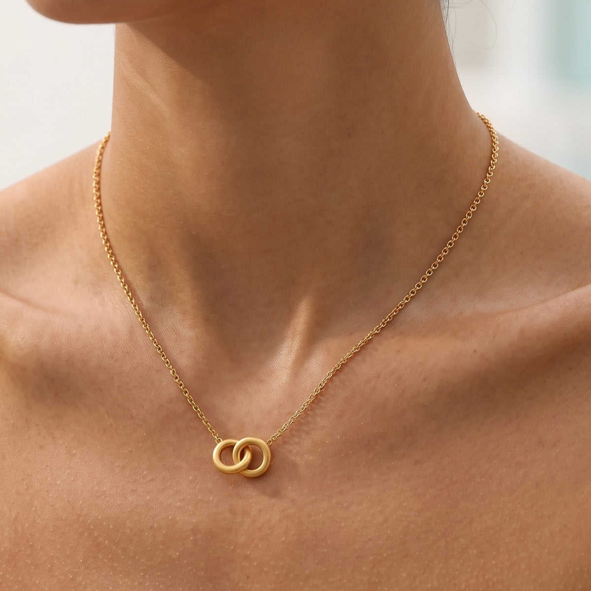 Close-up of the Gold Interlock Necklace at the collarbone showing two interlocking rings
