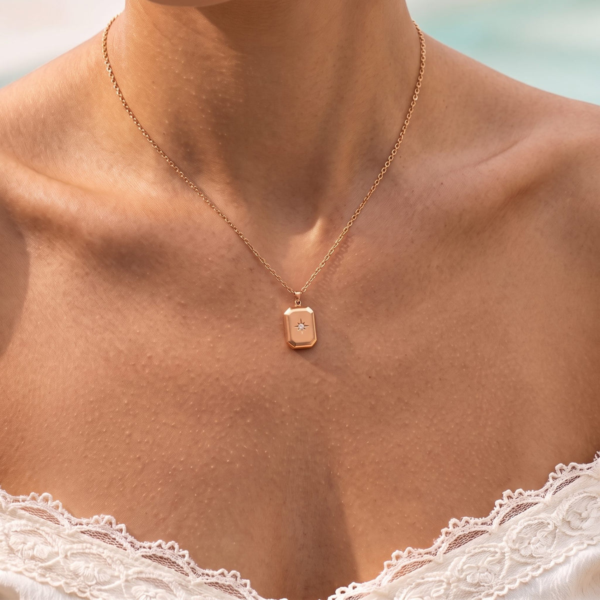 Close-up of the Star Pendant in rose gold, a star-set tag on a fine chain with the sea behind