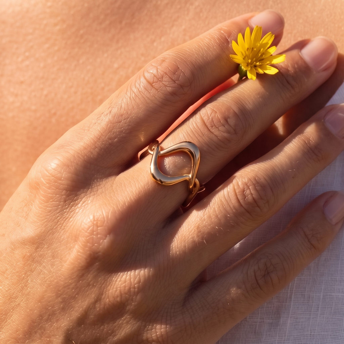 Close-up of the rose gold Twisted Wave Ring on a ring finger in warm natural light