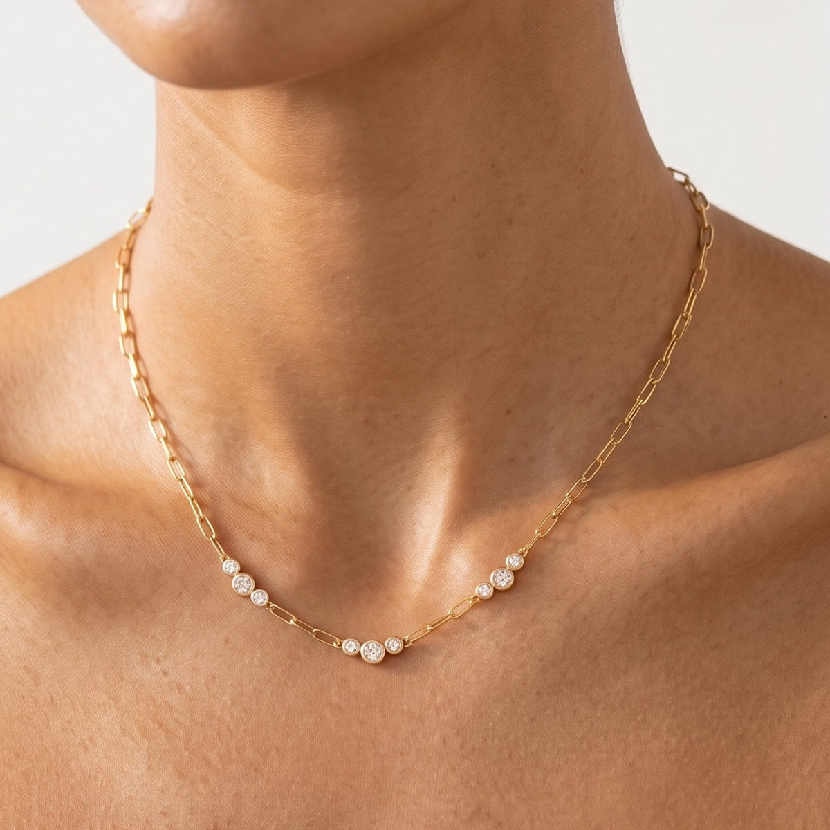Close-up of the Graduated Trio Necklace at the collarbone, highlighting bezel-set crystals on a paperclip chain