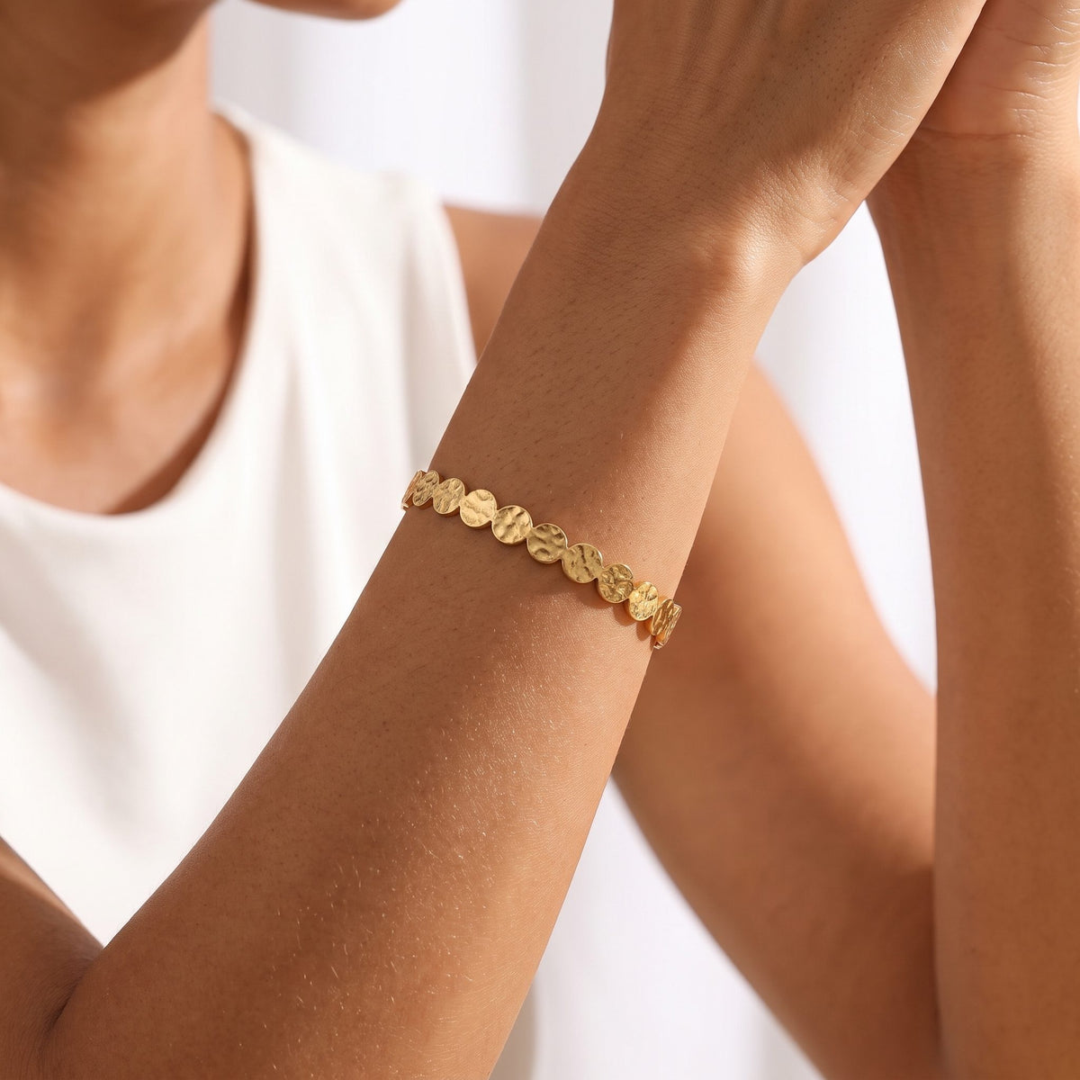Woman wearing the Hammered Disc Cuff on the wrist, her hands clasped together