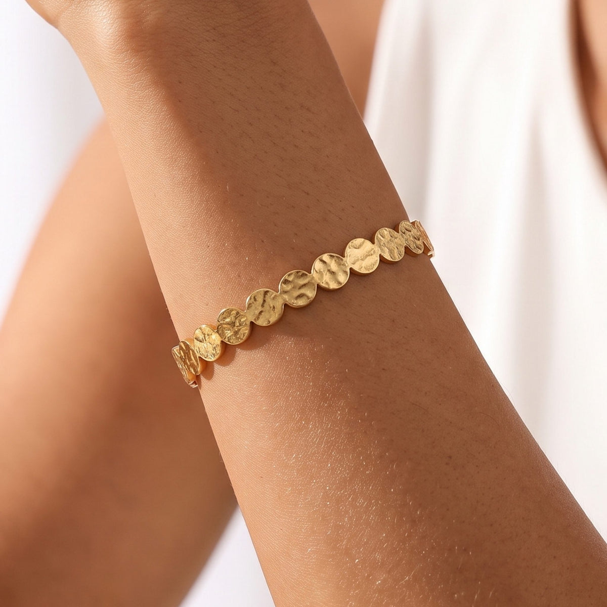 Close-up of the Hammered Disc Cuff on the wrist, showing its textured gold disc pattern