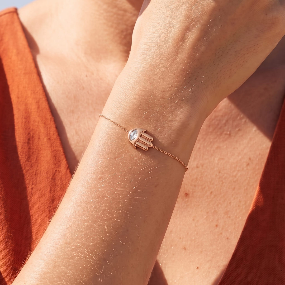 Close-up of the Hamsa Charm Bracelet on the wrist, showcasing its clear crystal eye setting, in rose gold