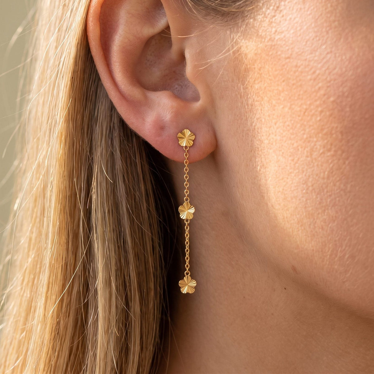 Woman wearing the Juliette Floral Chain Earrings hanging below the lobe with gold flower charms
