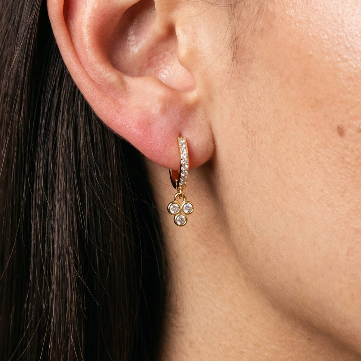 Woman wearing the Juliette Triple Stone Earrings hanging below the lobe with a gold three-stone charm