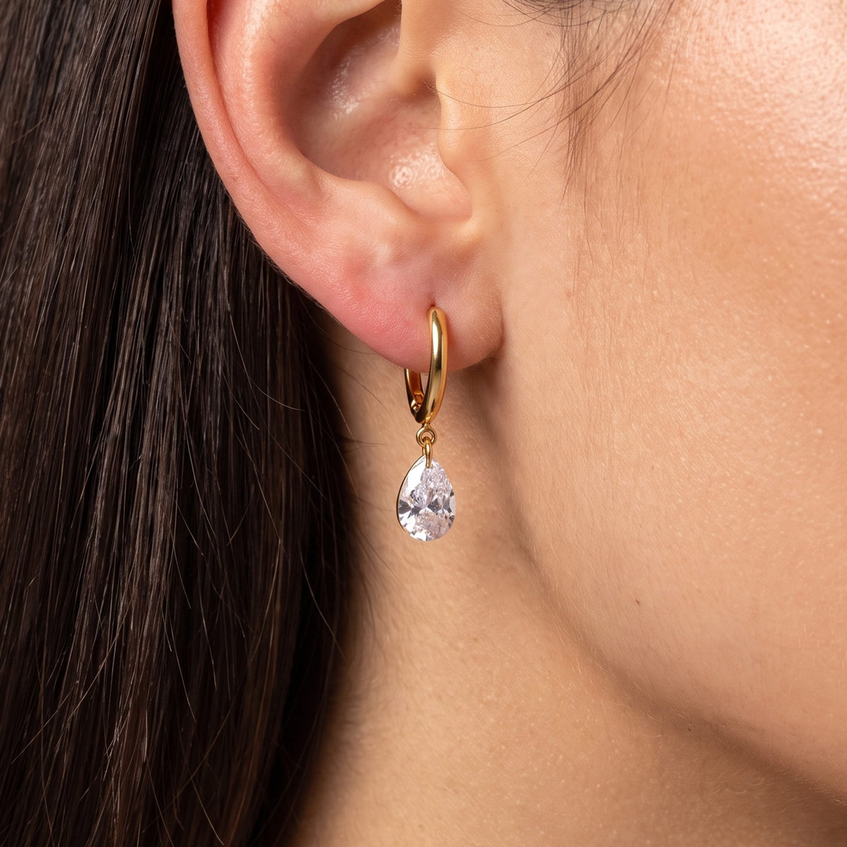 Close-up of the Large Teardrop Huggies on the ear showing a dangling crystal teardrop charm