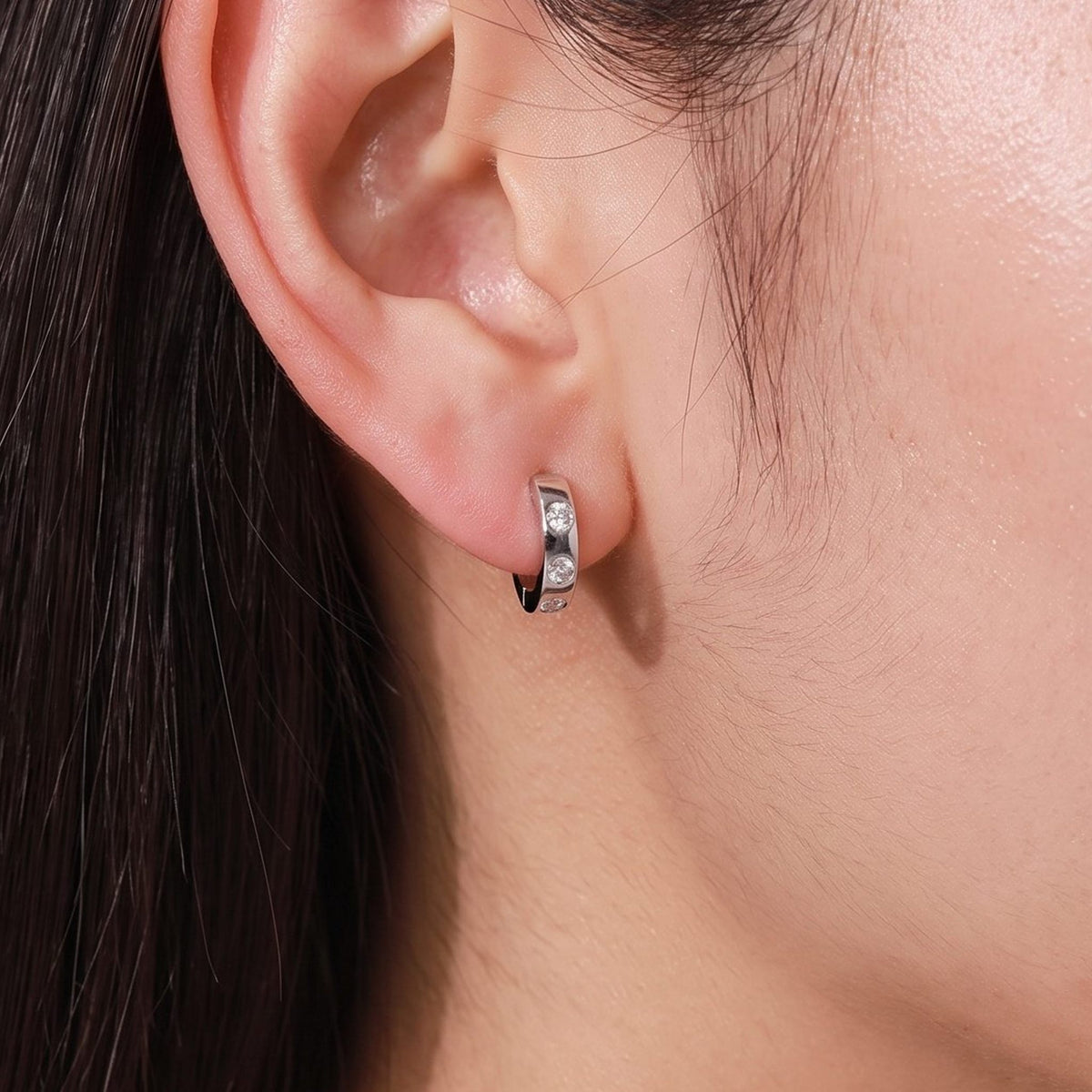 Woman wearing the Lilou Minimalist Silver Hoops on the lobe with three small inset crystals