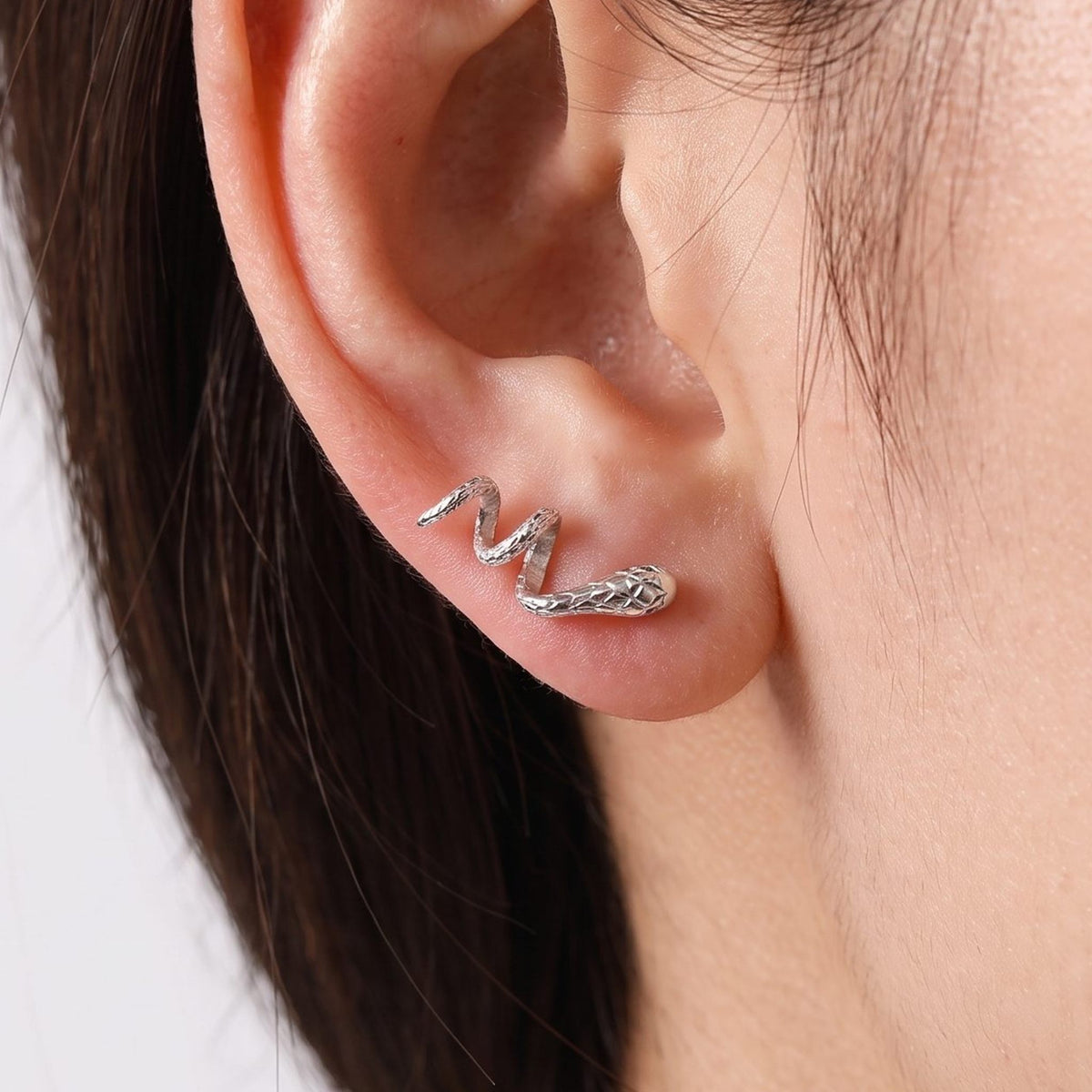 Woman wearing the Lilou Silver Snake Earrings curving along her ear lobe