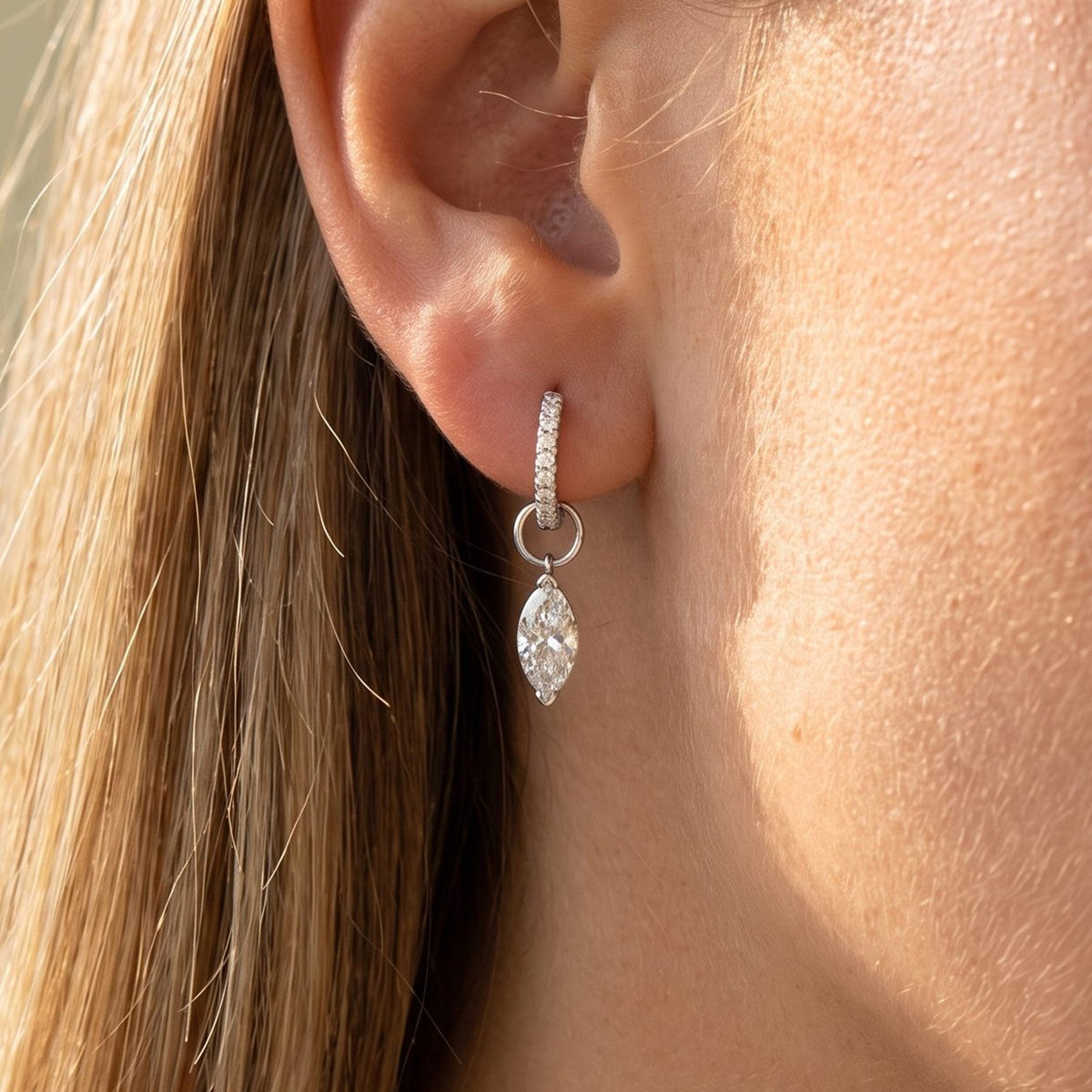 Woman wearing the Luna Pavé Drop Earrings hanging below the lobe with a silver marquise-cut charm