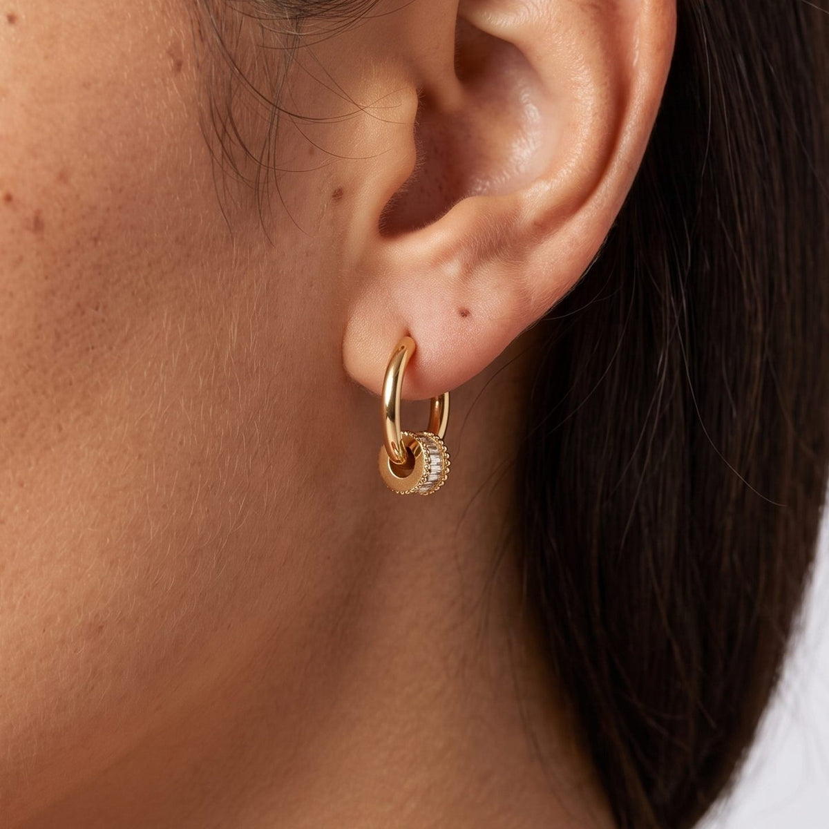 Woman wearing the Maia Crystal Earrings through the lobe with a small crystal-lined gold charm