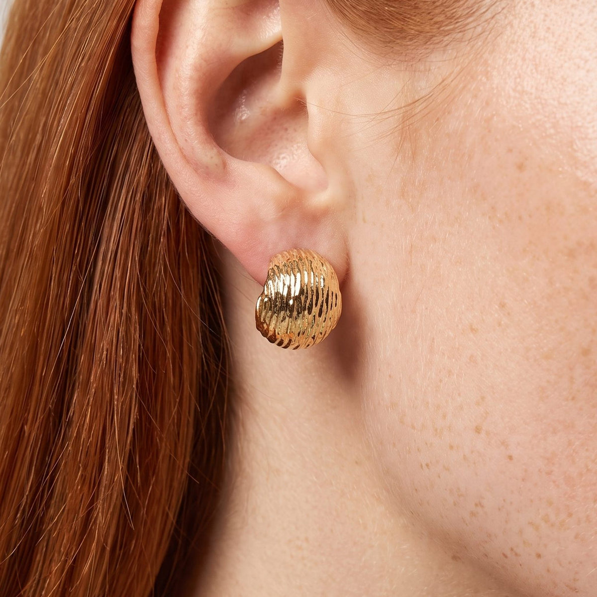 Woman wearing the Mariah Gold Earrings on the lobe, featuring a textured ribbed dome design