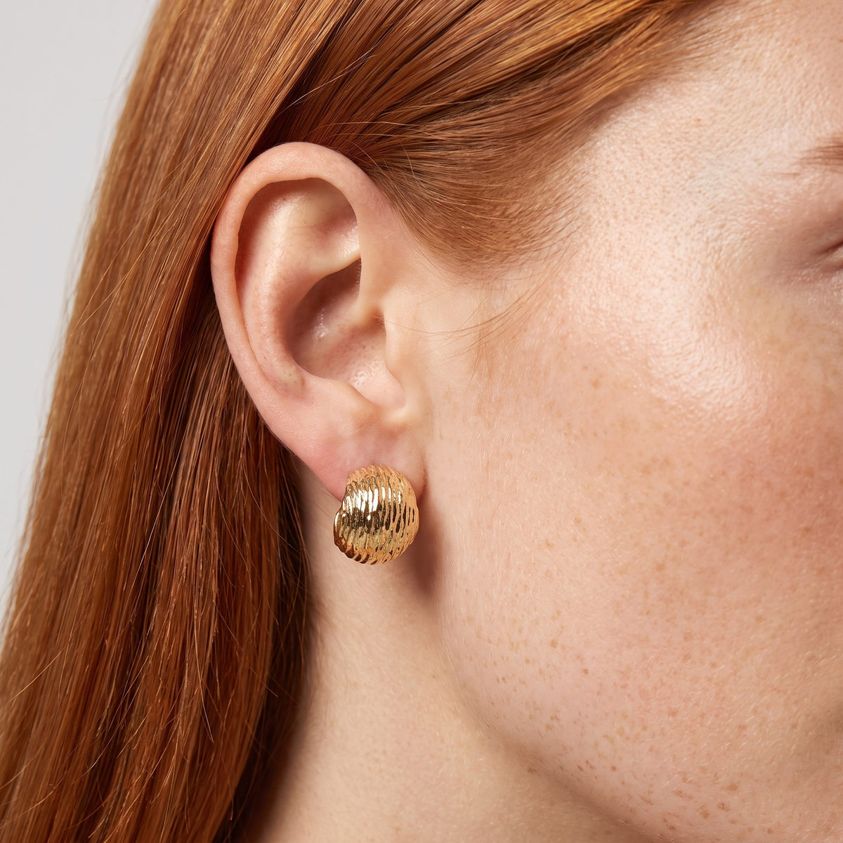 Woman wearing the Mariah Gold Earrings on the lobe, featuring a textured ribbed dome design