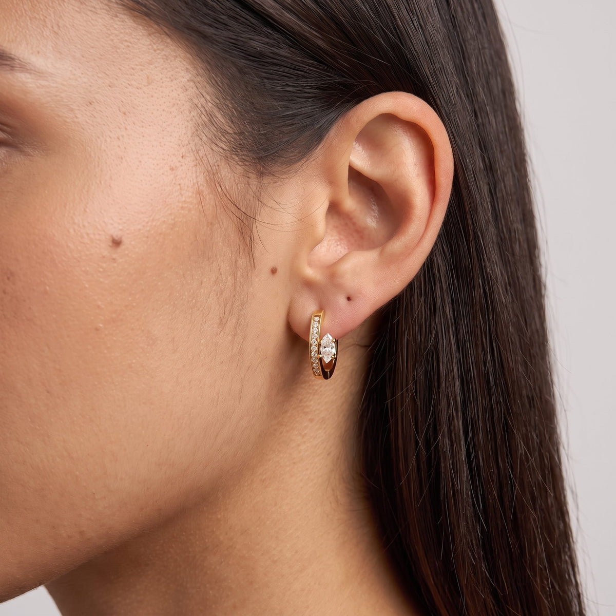 Woman wearing the Marquise Pavé Hoops on the ear with dark hair tucked behind