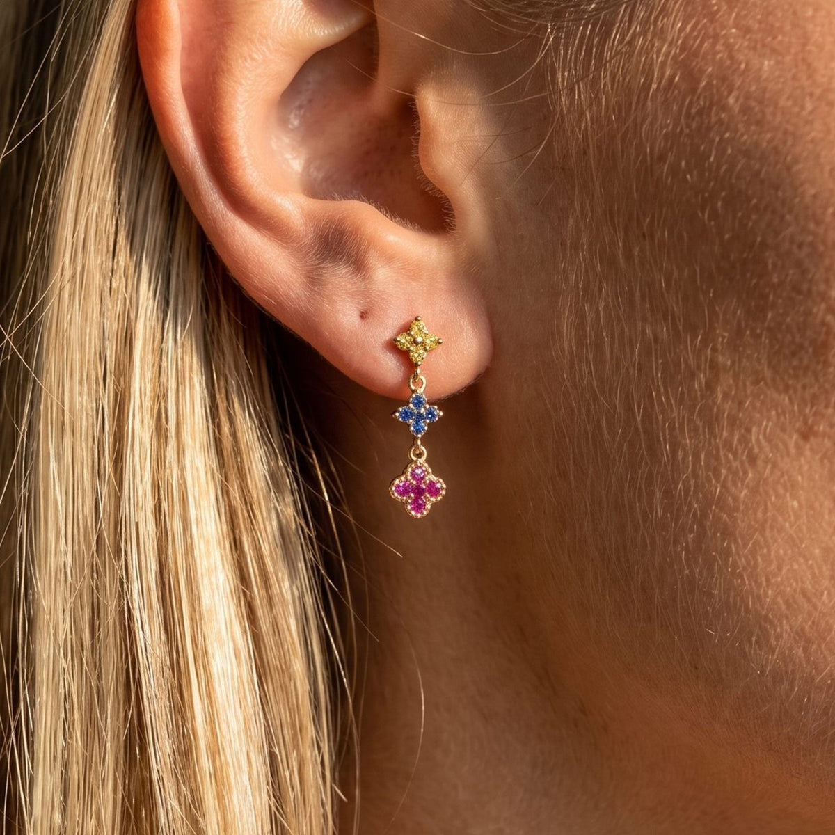 Woman wearing the Mia Glimmer Cluster Earrings hanging below the lobe with colorful flower-shaped charms