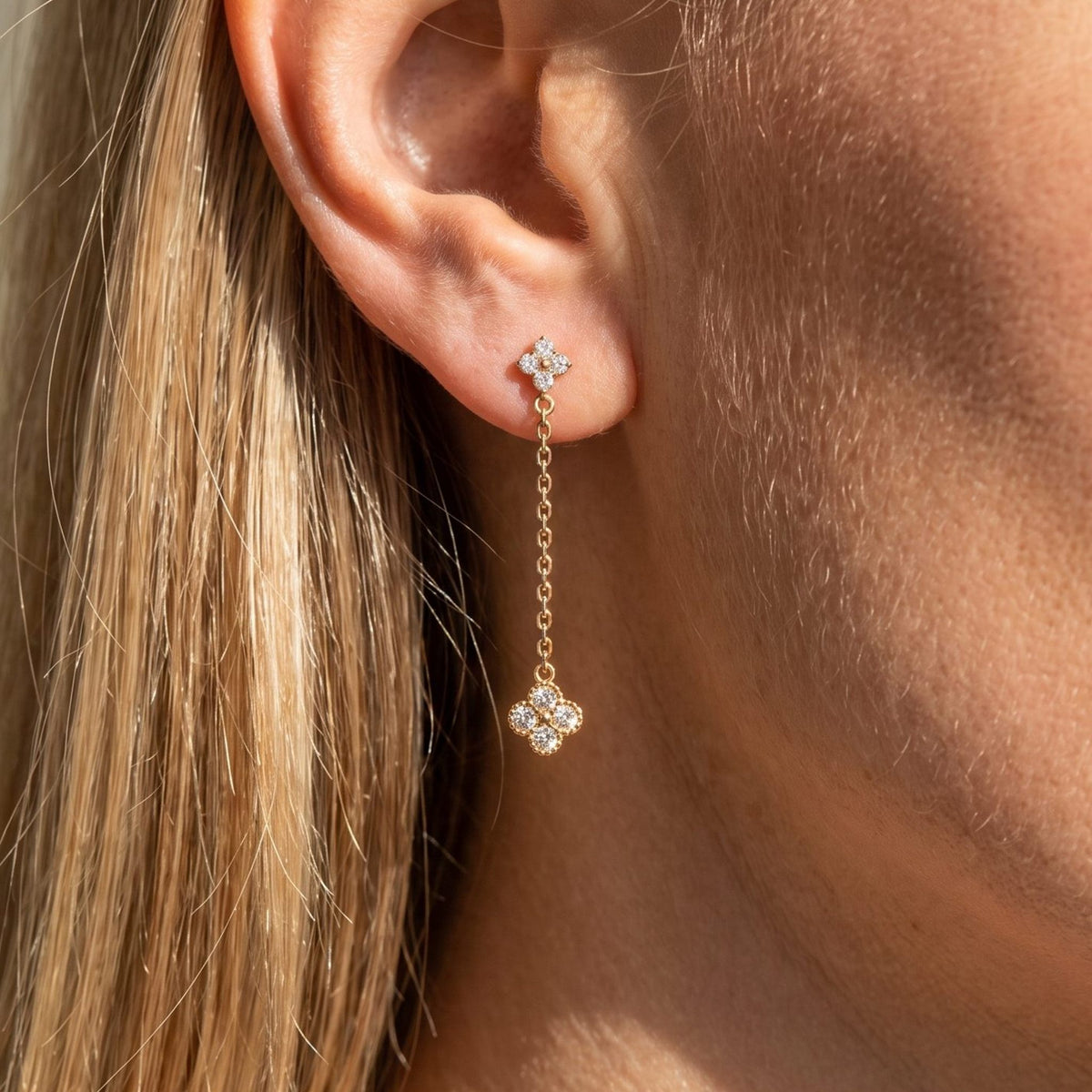 Woman wearing the Mia Sparkle Drop Earrings hanging below the lobe with gold flower charms