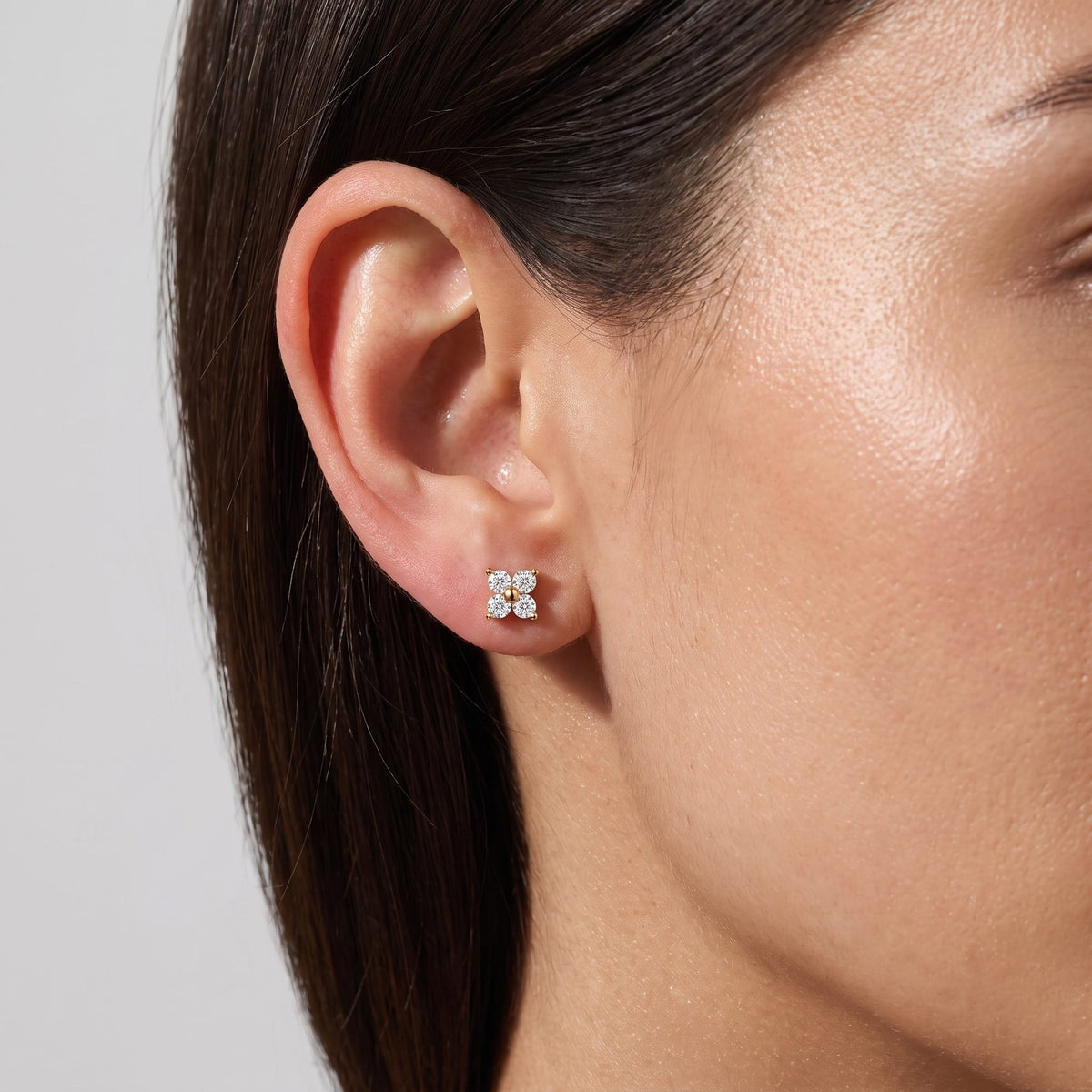 Woman wearing the Noemi crystal clover gold stud earrings, the clover sitting flat to the lobe