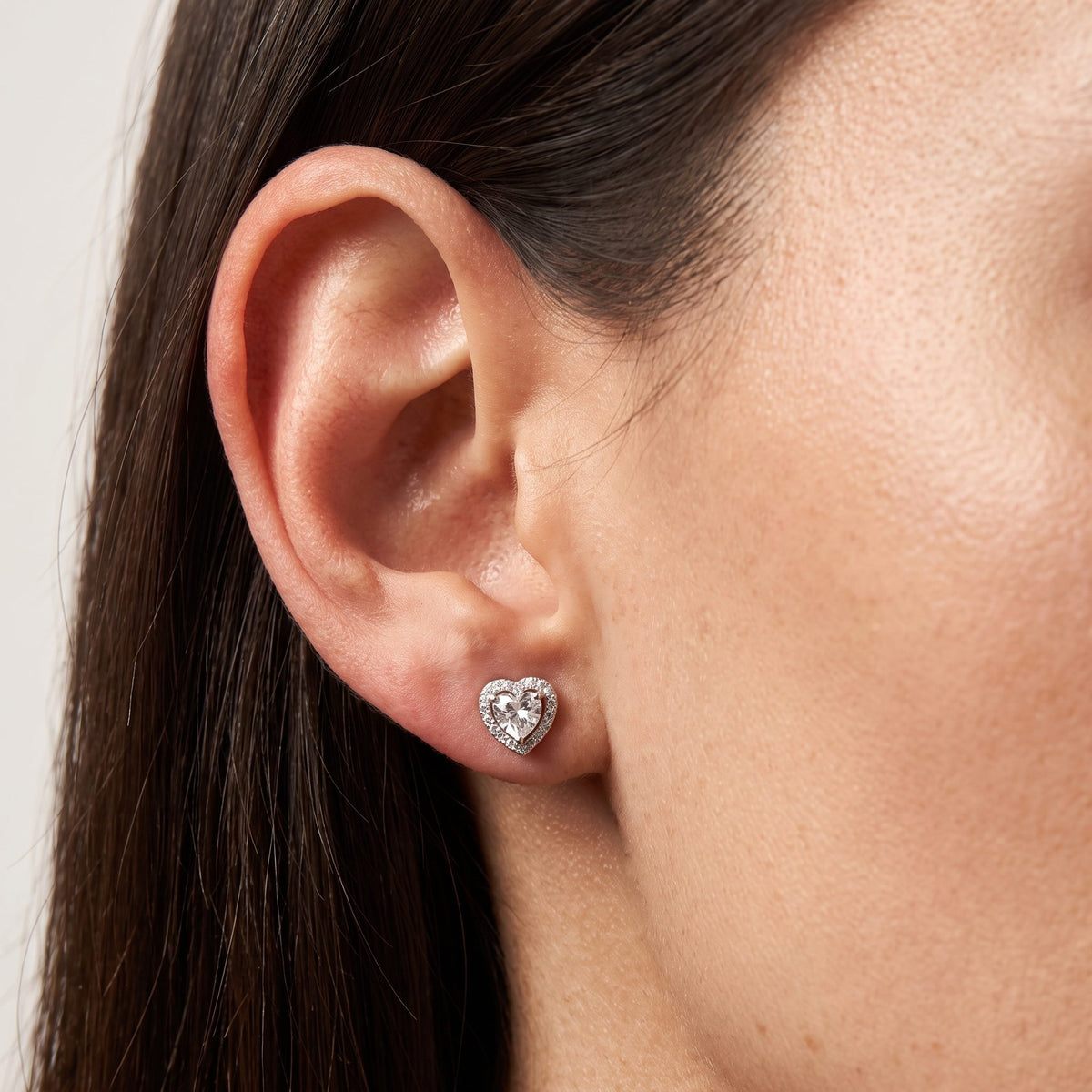 Woman wearing the Olivia Amour Halo Earrings flat to the lobe, featuring a silver-colored heart-shaped crystal